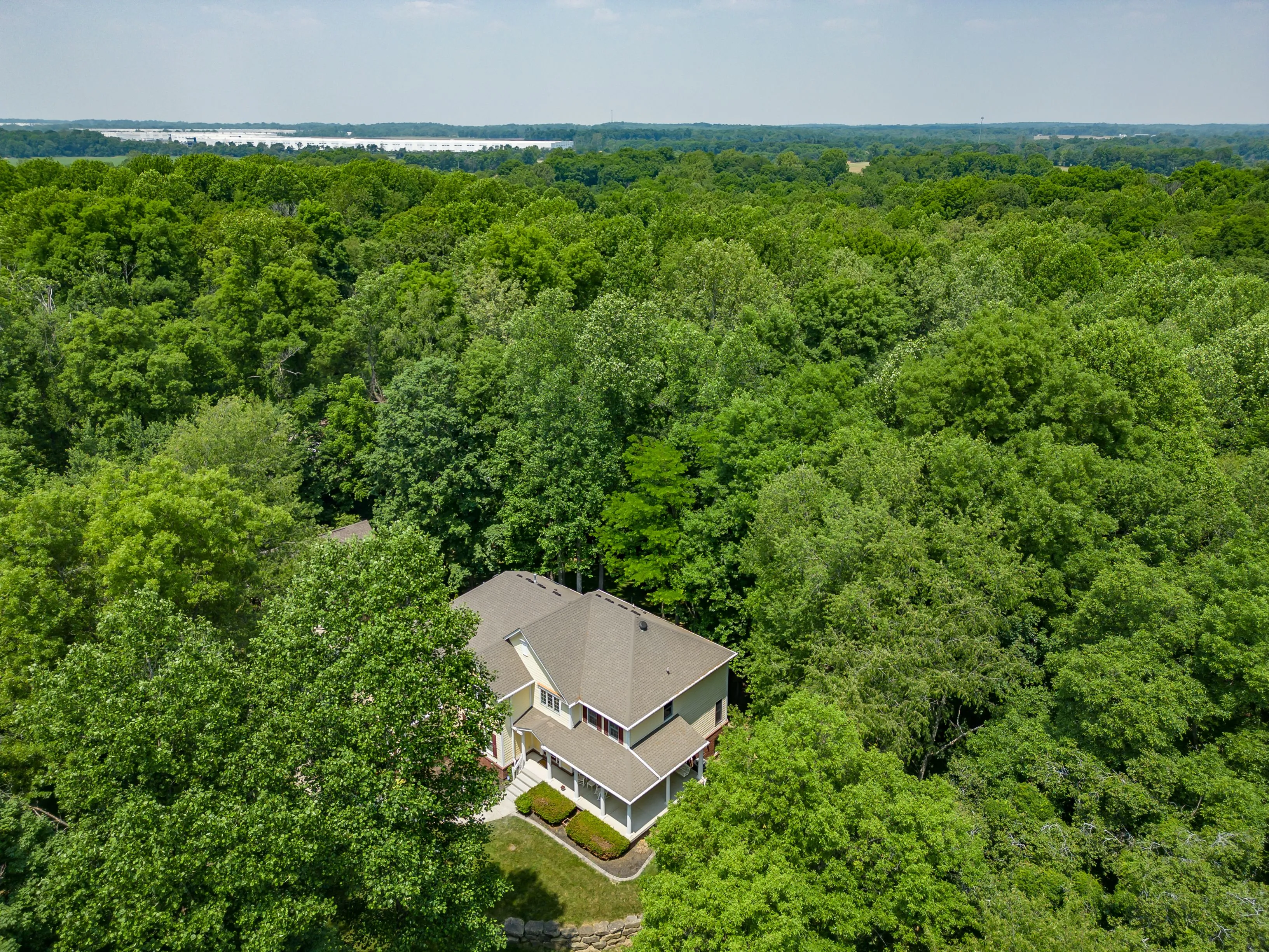 Aerial view of an isolated house surrounded by a dense green forest.