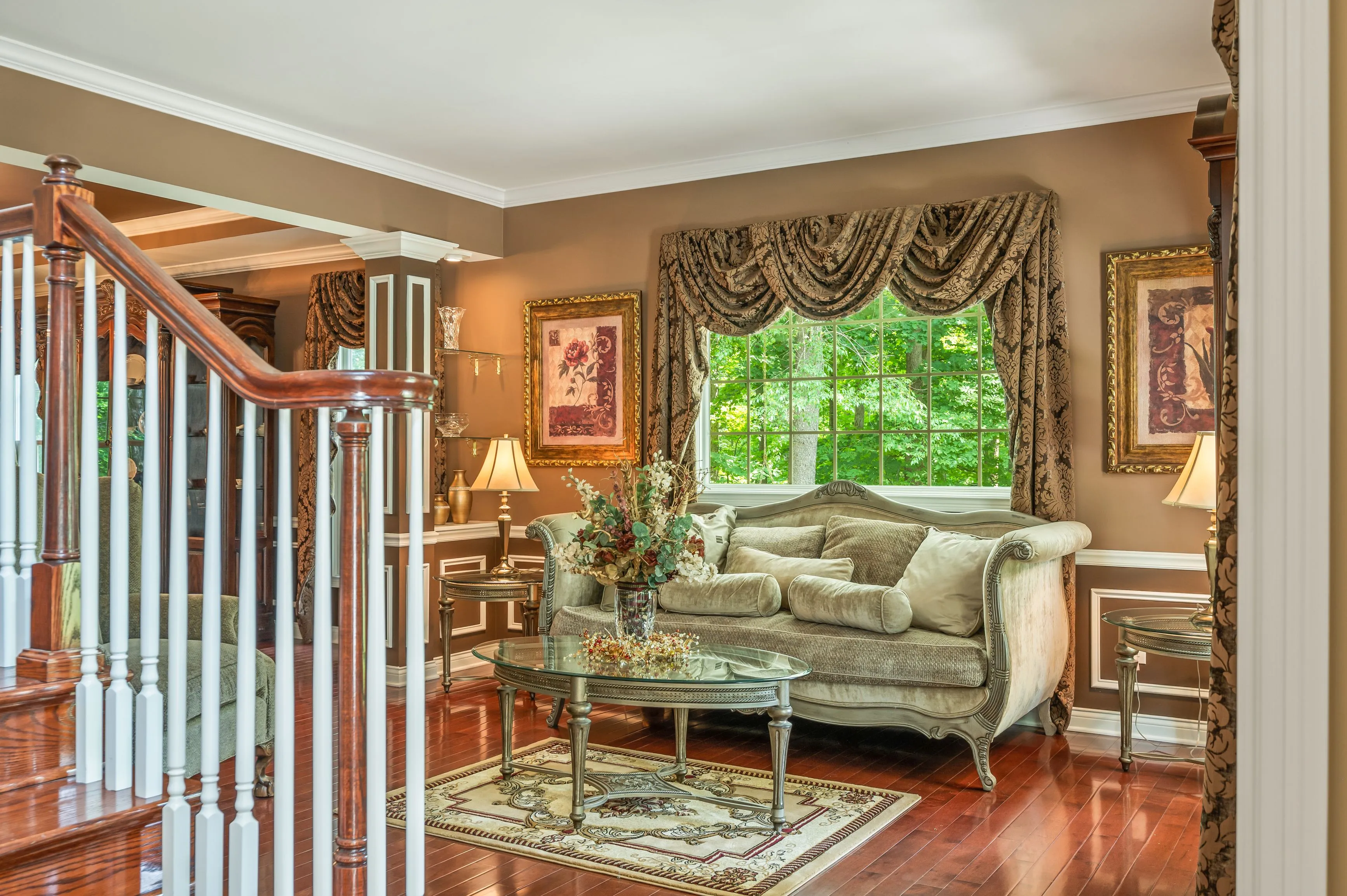 Elegant living room interior with large windows, traditional furniture, and hardwood floors.
