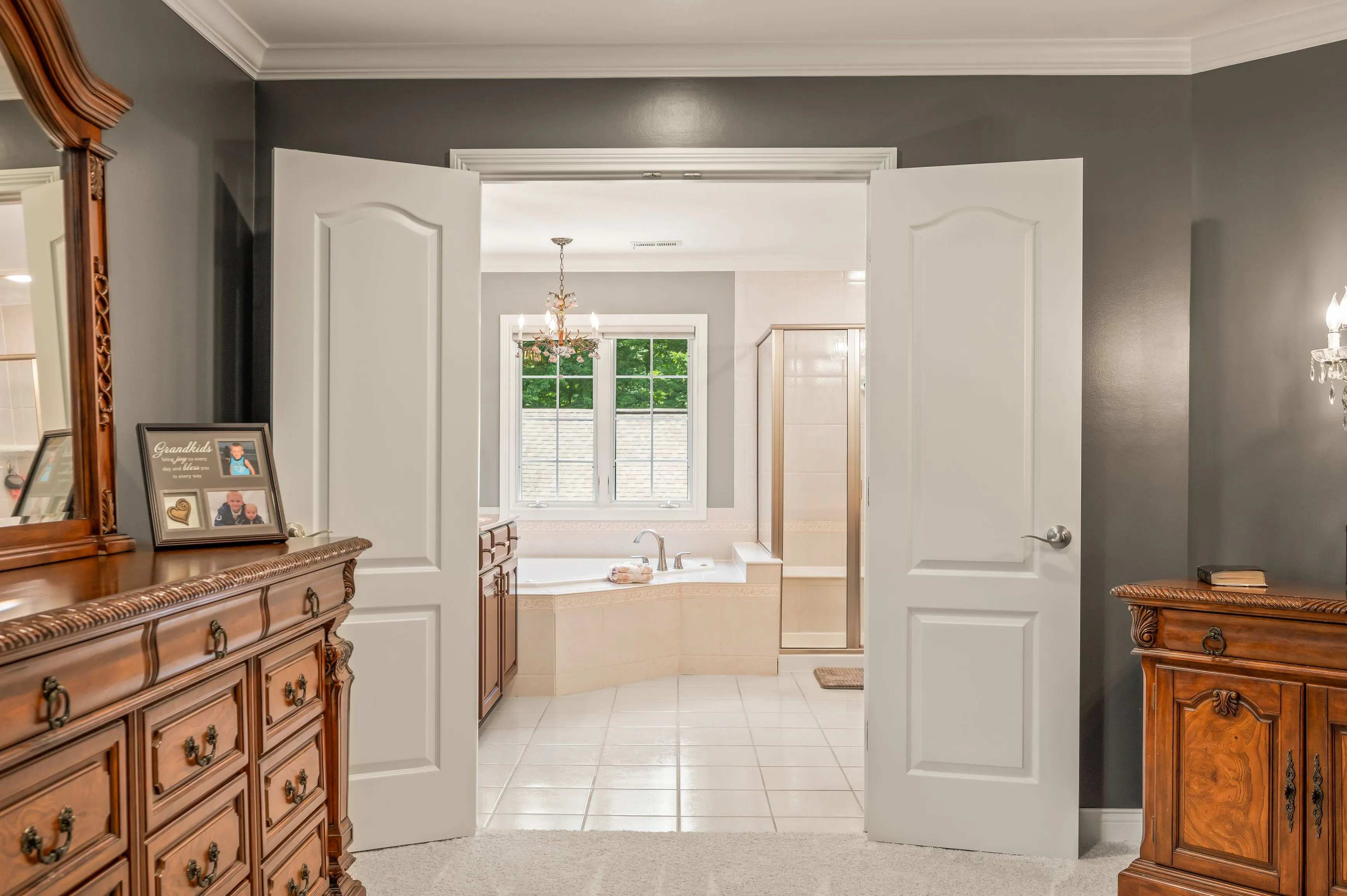 Elegant bathroom interior with double vanity, tiled flooring, and a bathtub near a window.