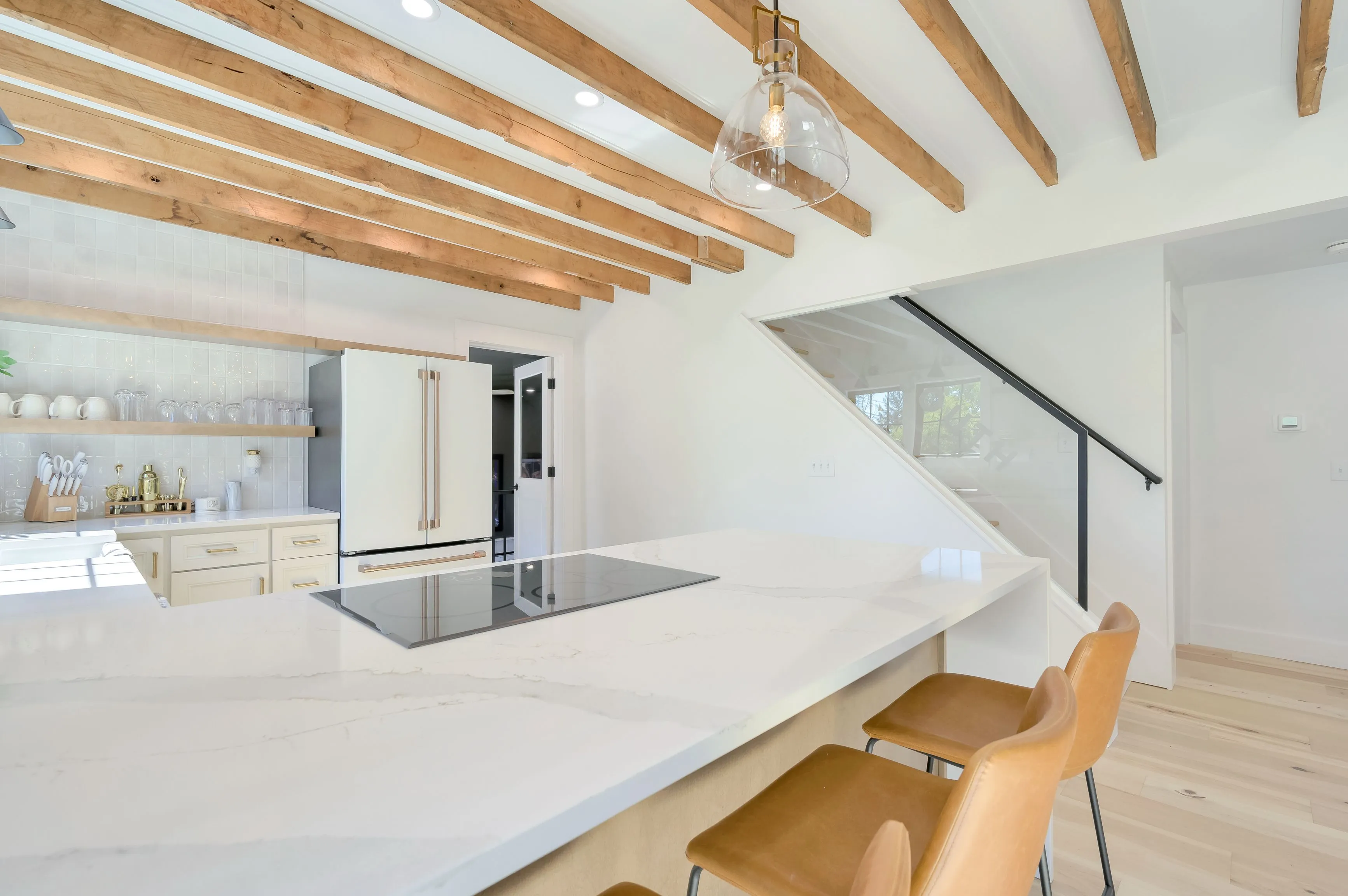 Modern kitchen interior with a large central island, wooden beams on the ceiling, and minimalist design.