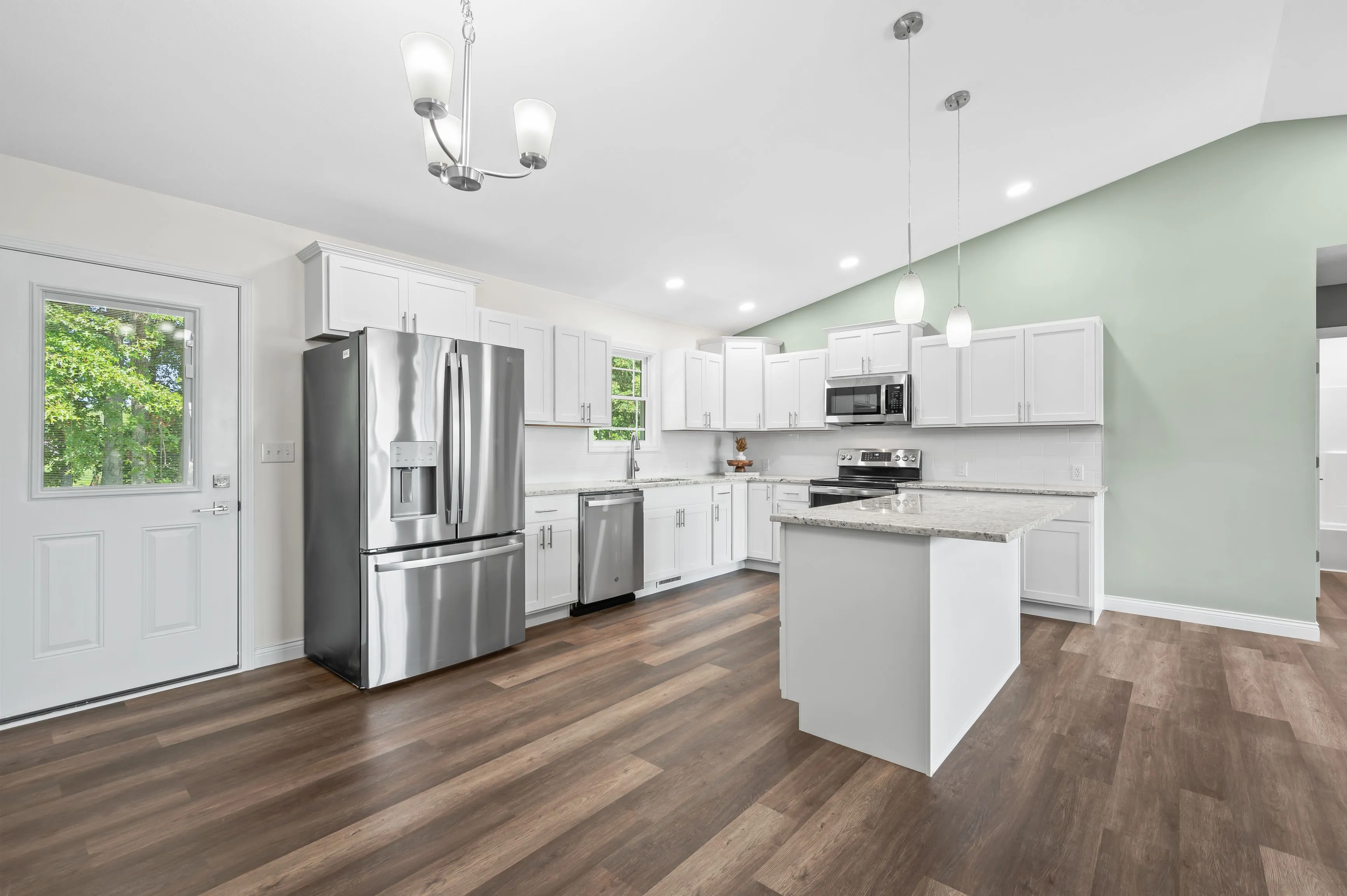 Spacious modern kitchen with white cabinetry, stainless steel appliances, and hardwood floors.