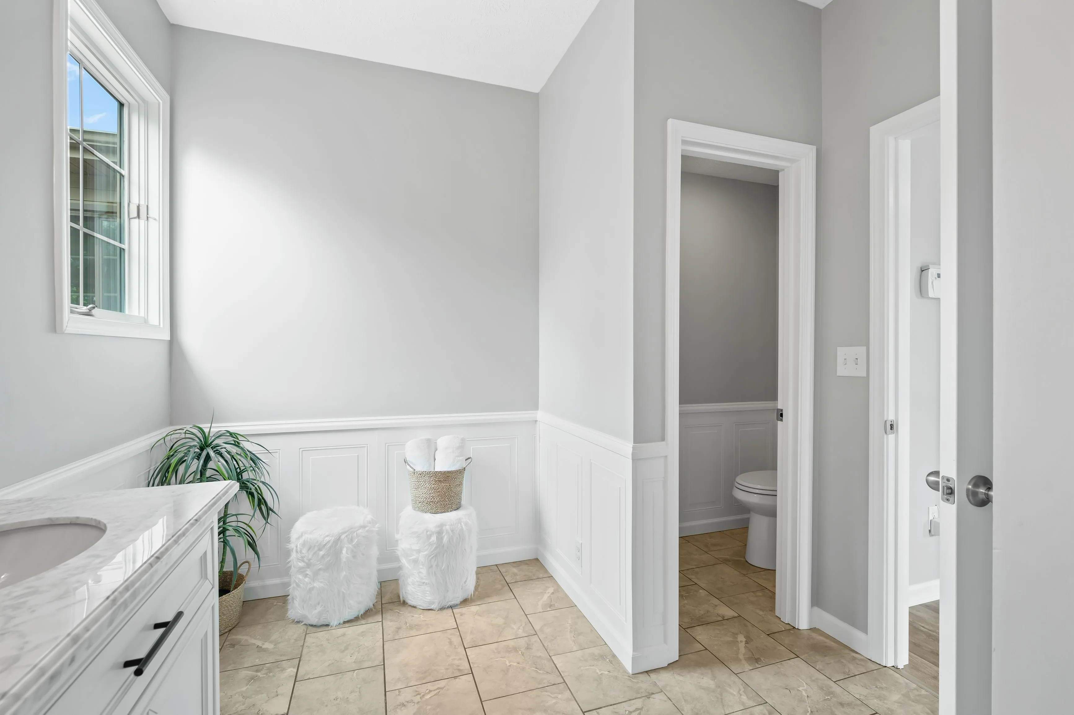 Bright bathroom interior with a dual sink vanity, large mirror, bathtub, and separate toilet room.