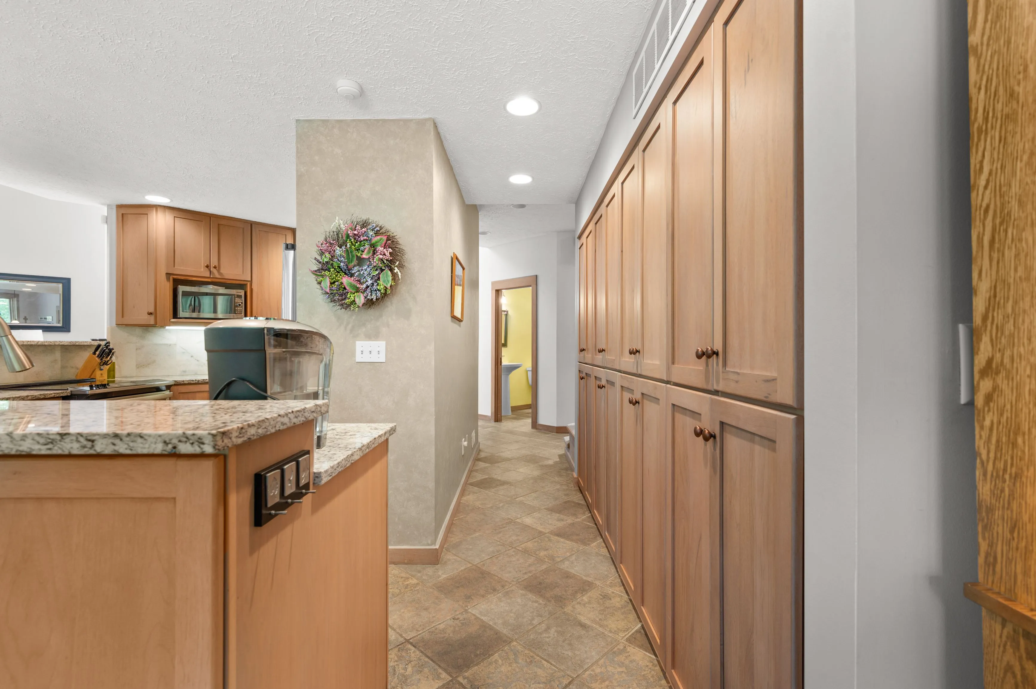 Interior view of a home hallway featuring built-in wood cabinets on the right and a kitchen area with countertops on the left.