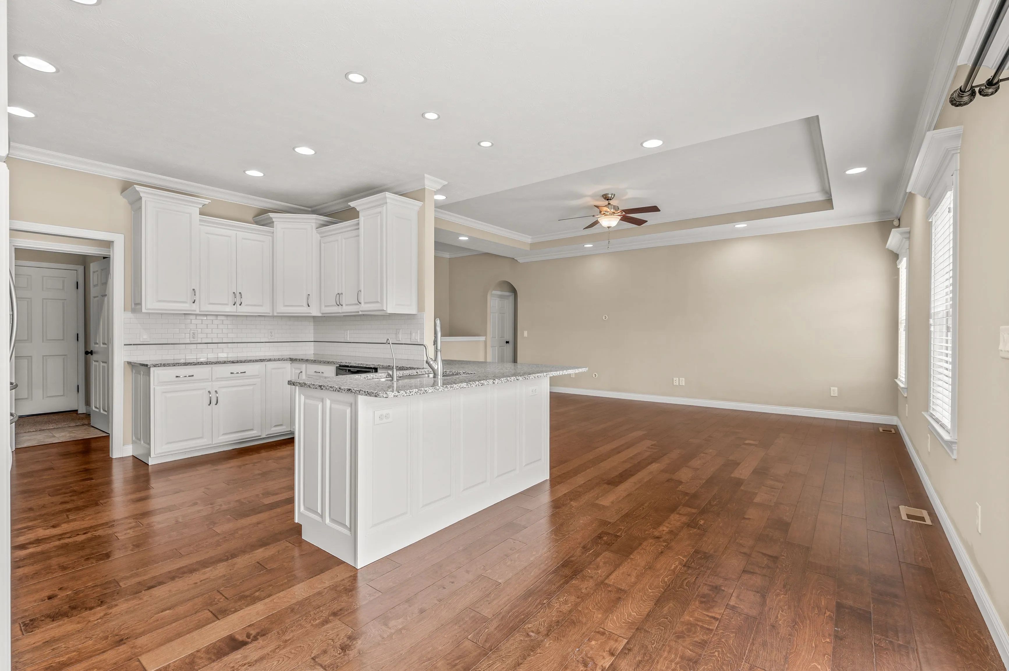 Spacious kitchen interior with hardwood floors, white cabinetry, and central island in a modern home.