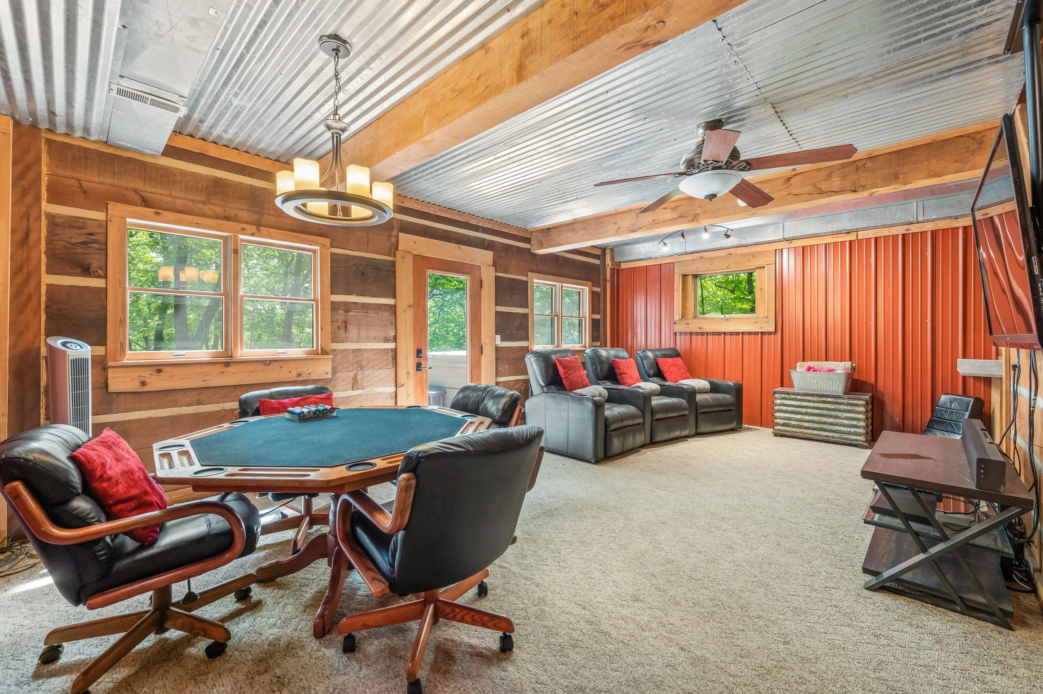 Cozy rustic game room with poker table, leather reclining chairs, corrugated metal ceiling, and wooden walls.