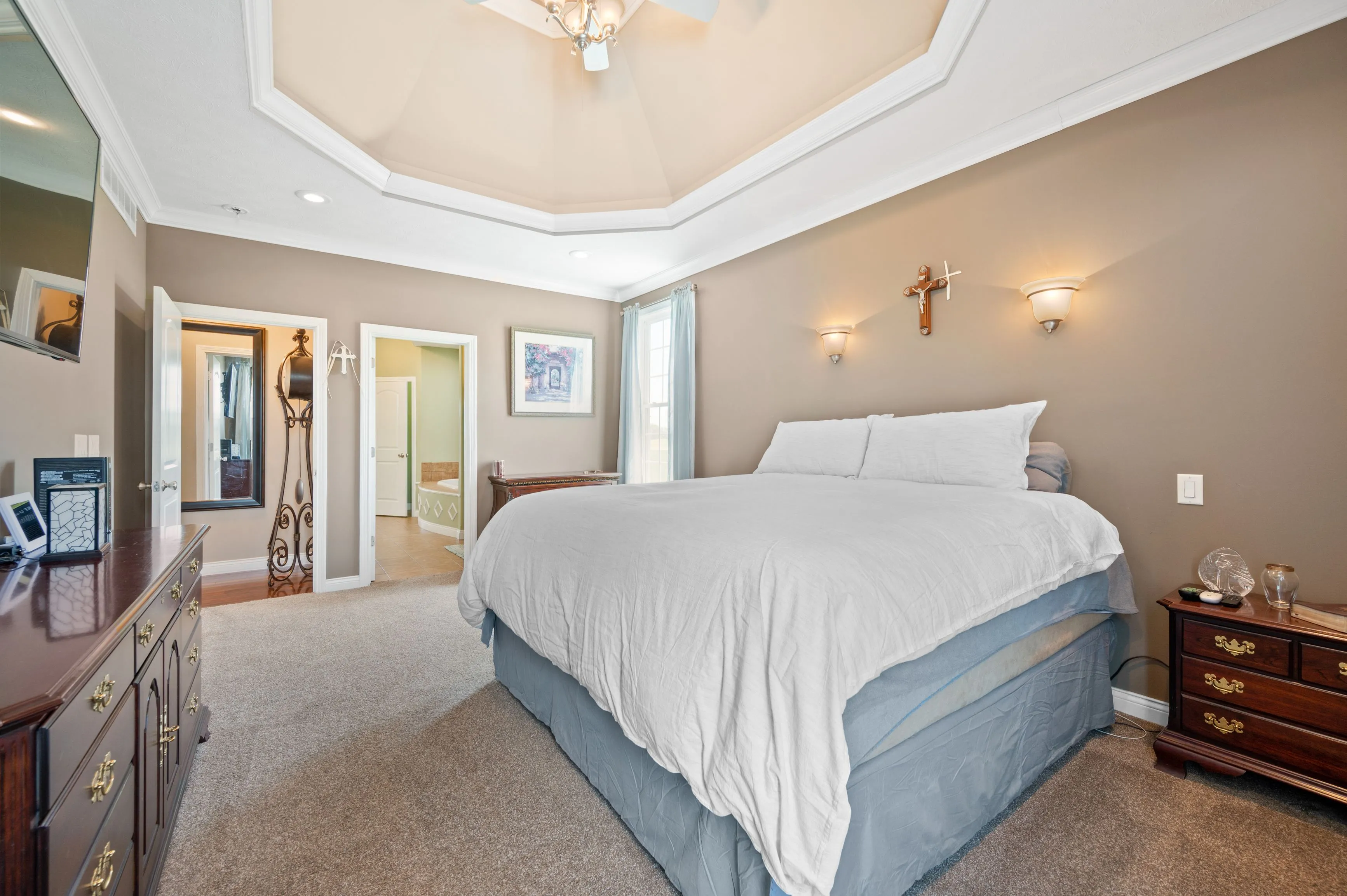 Elegant bedroom interior with a large bed, side tables, and a tray ceiling.