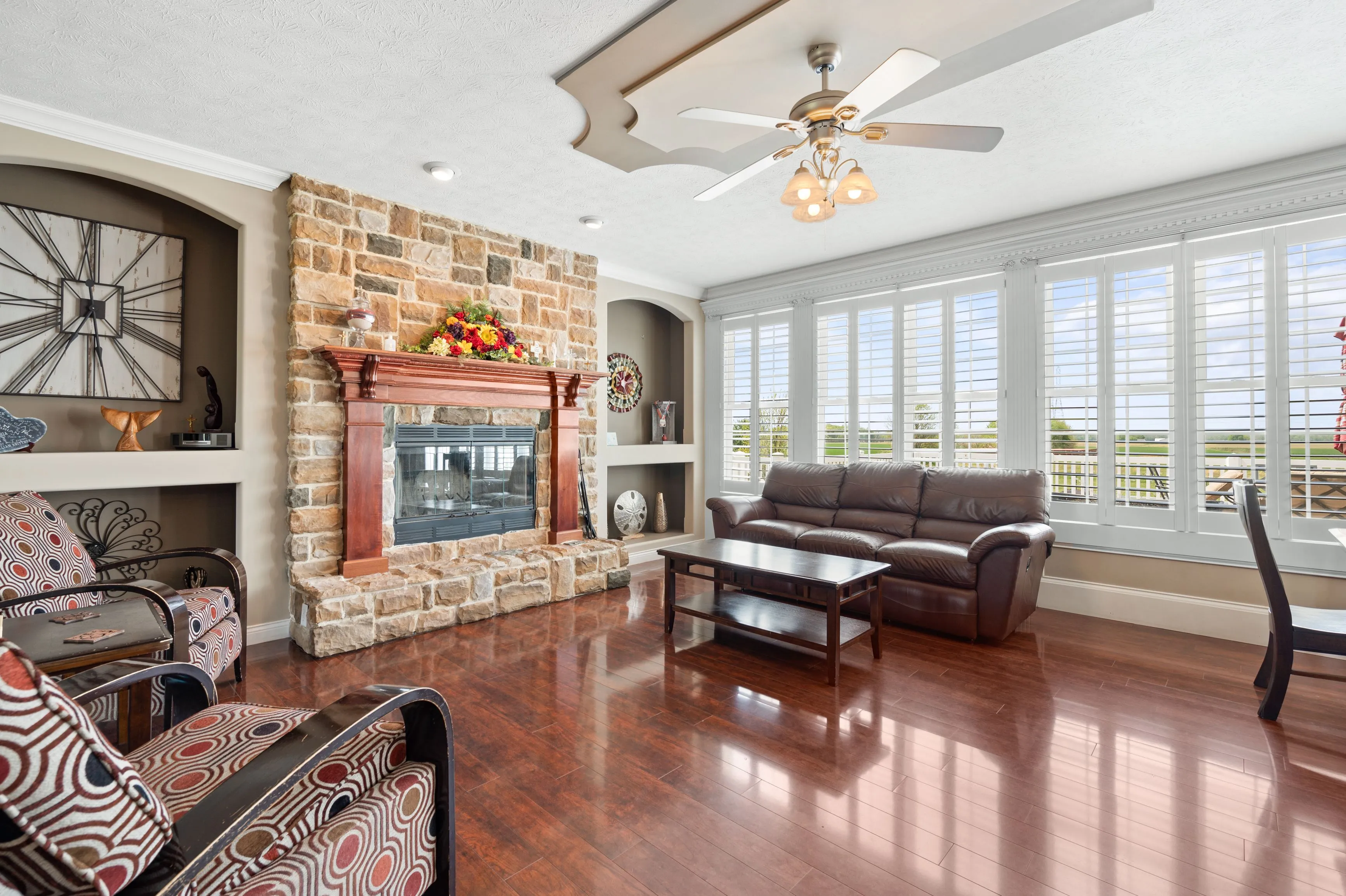 Elegant living room interior with polished hardwood floors, brick fireplace, large windows, and plush seating.