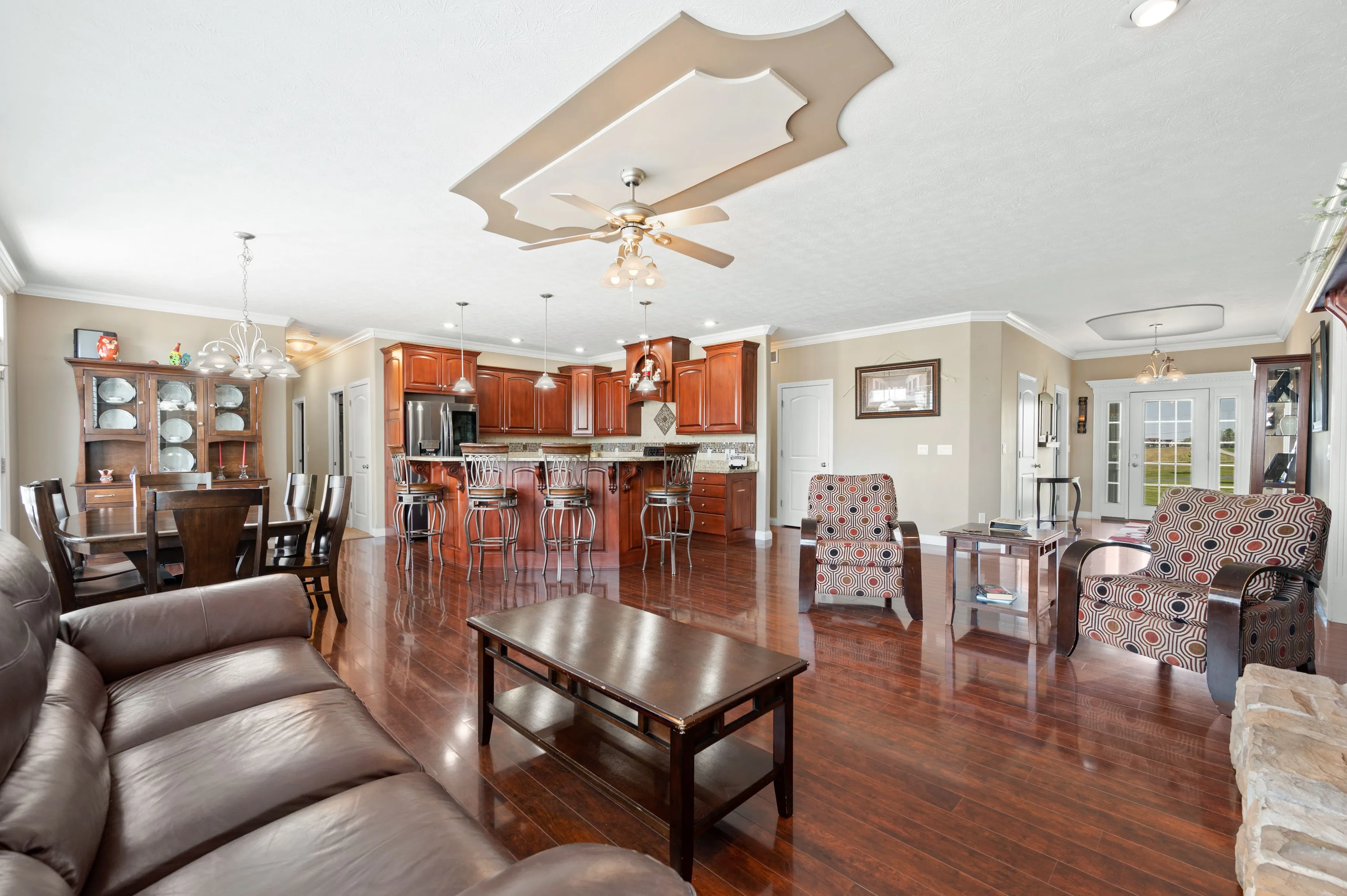 Spacious living room with hardwood floors, a ceiling fan, and an open concept kitchen with bar stools.