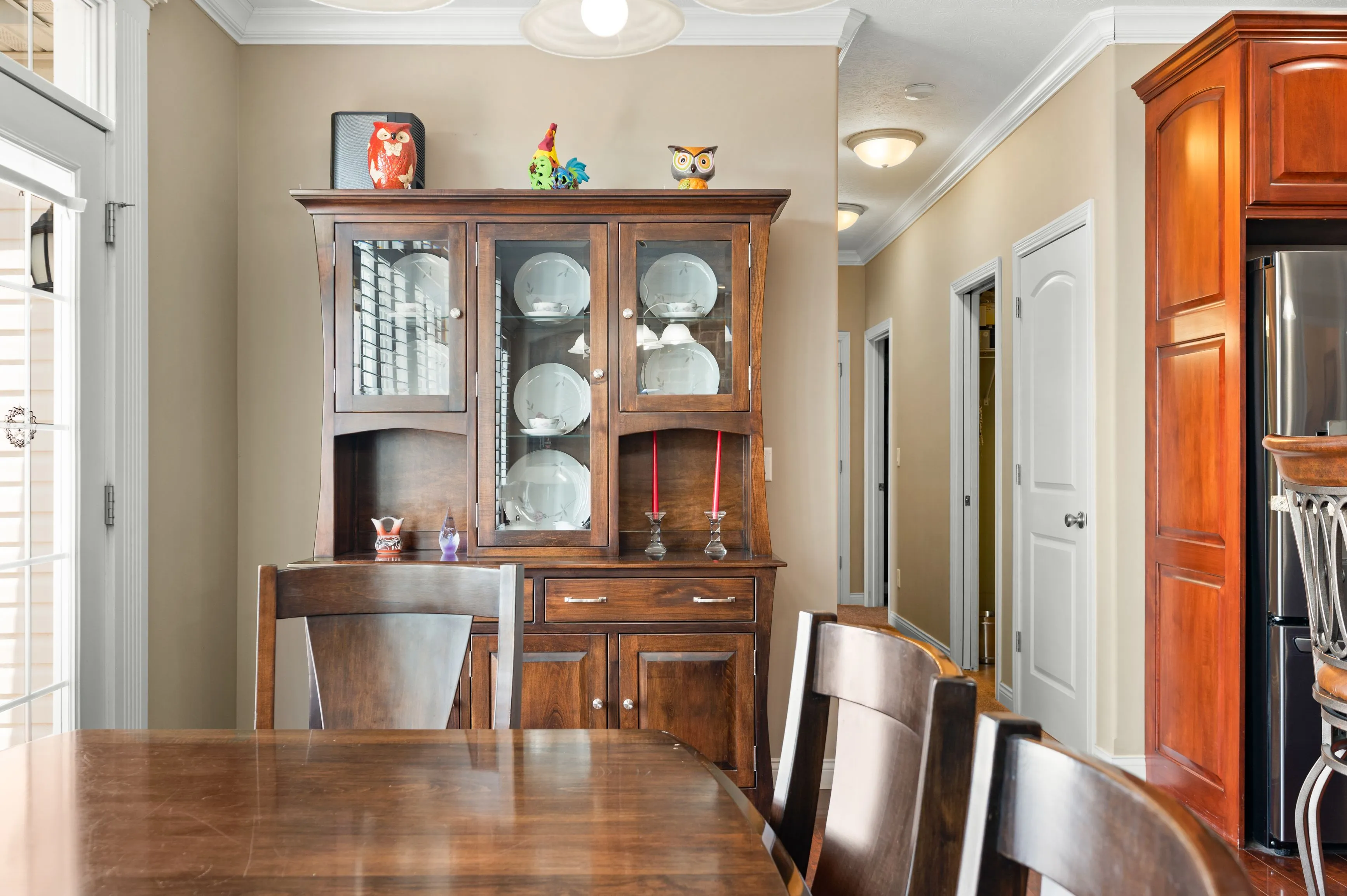 Cozy dining room with a wooden table, chairs, and a china cabinet displaying dishes and decorative items.