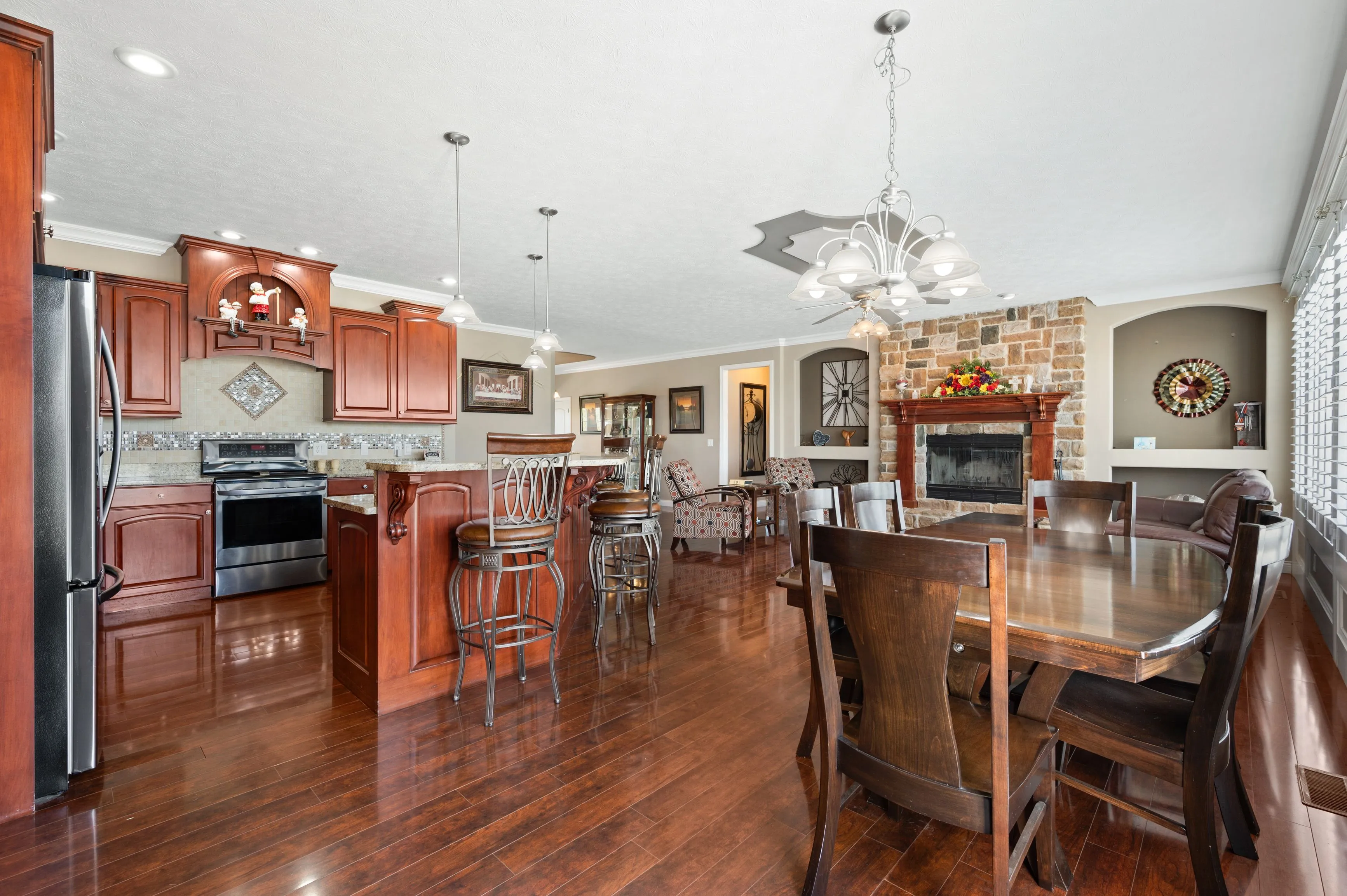 Spacious kitchen with wooden flooring, stainless steel appliances, wooden cabinets, and a dining area with a large table and chairs.