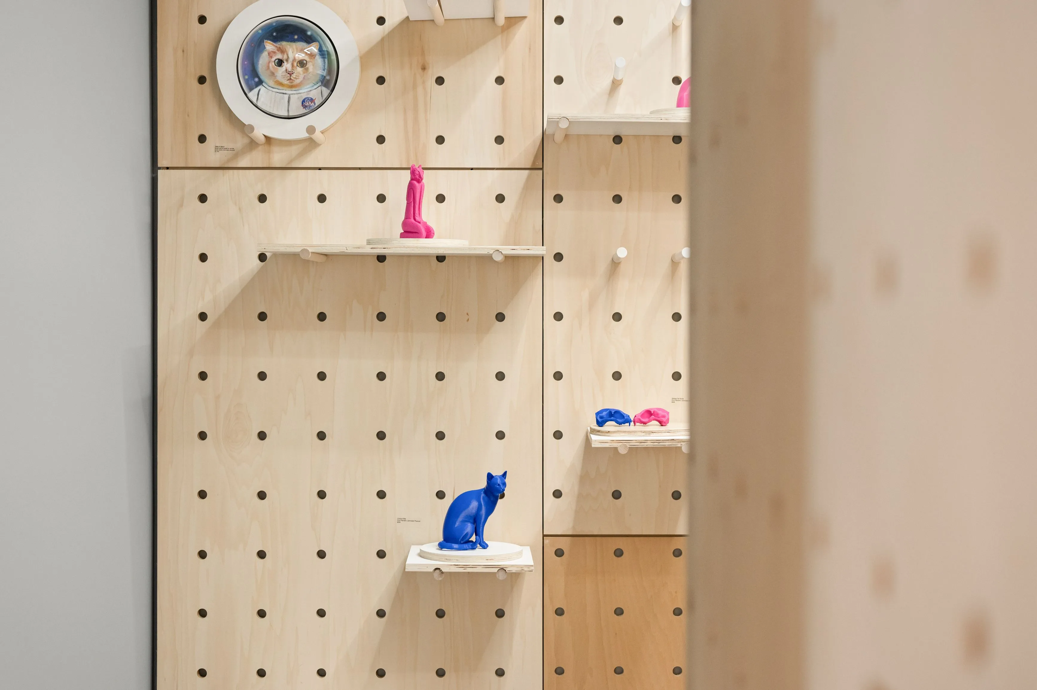 Interior view of a pegboard storage wall with a few items on the shelves, including a clock, small figurines, and a plant pot.