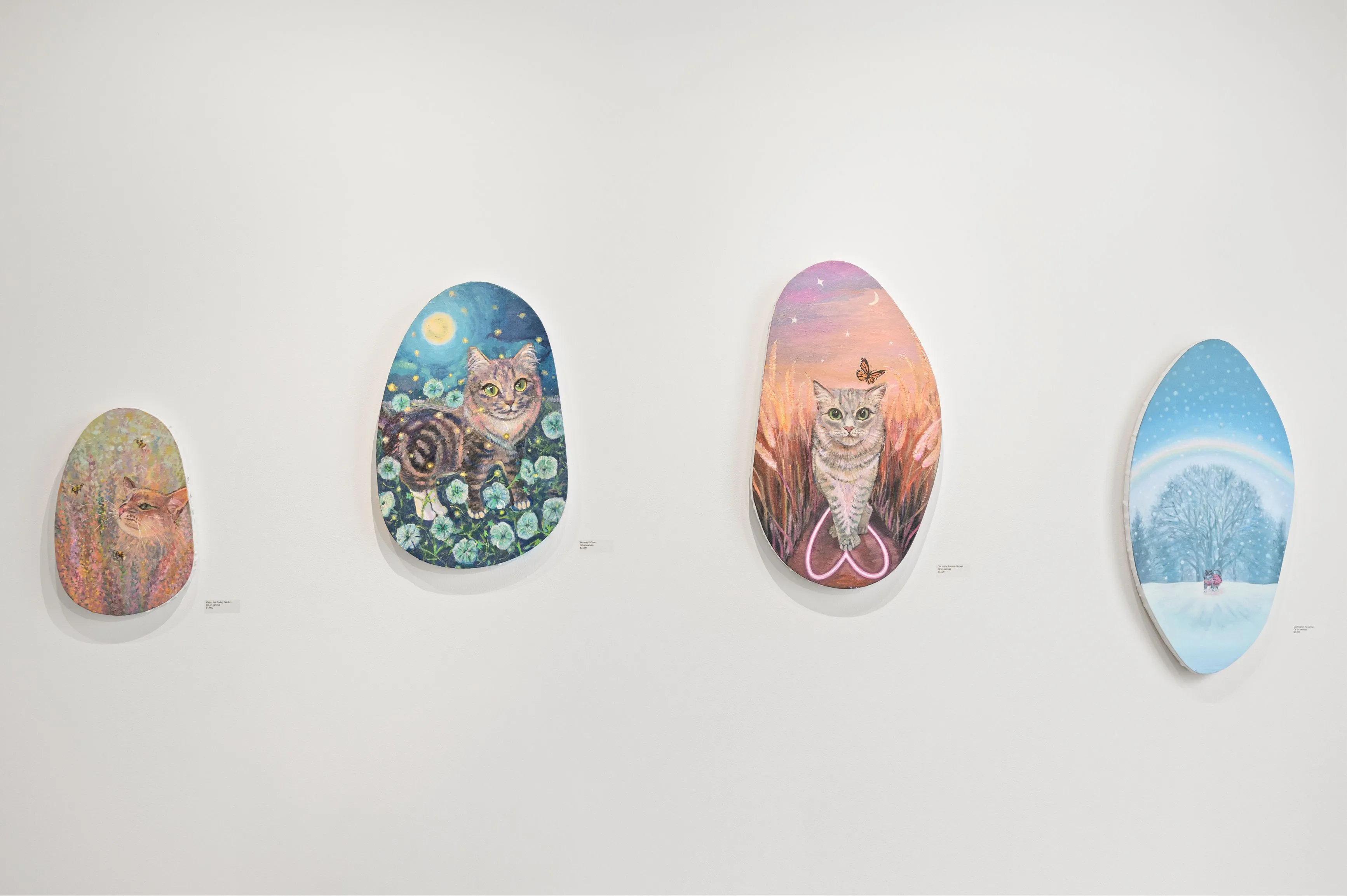 Four decorative Easter eggs with various patterns and illustrations displayed on a white wall.