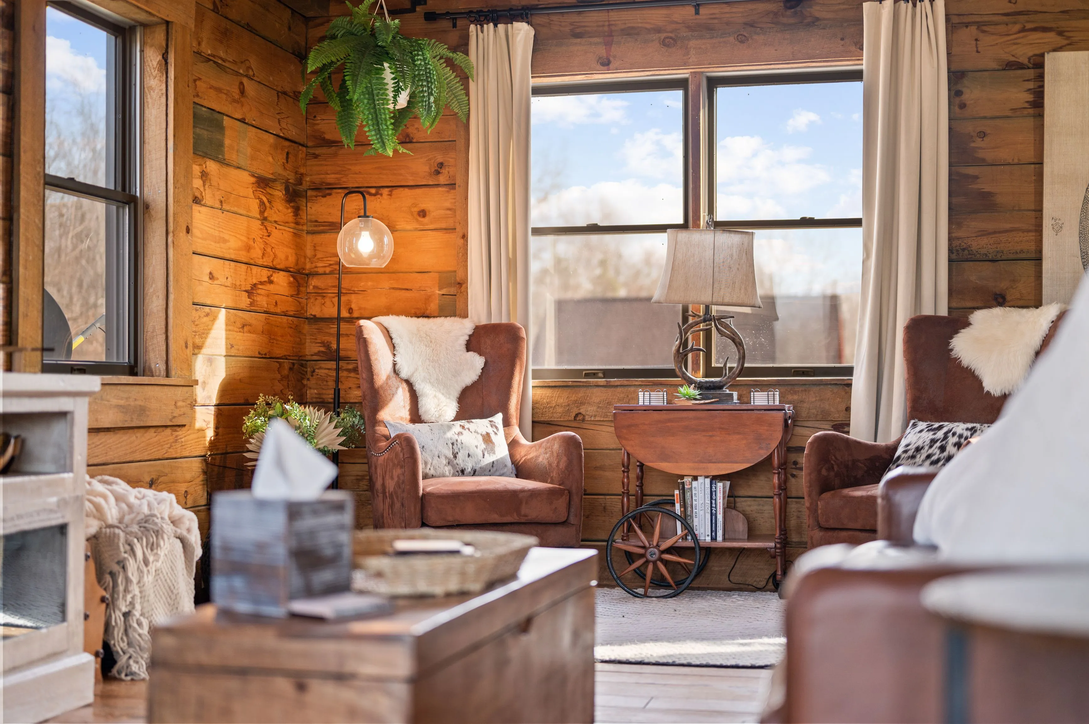 Cozy cabin living room with wooden walls, leather chairs, and a fireplace.