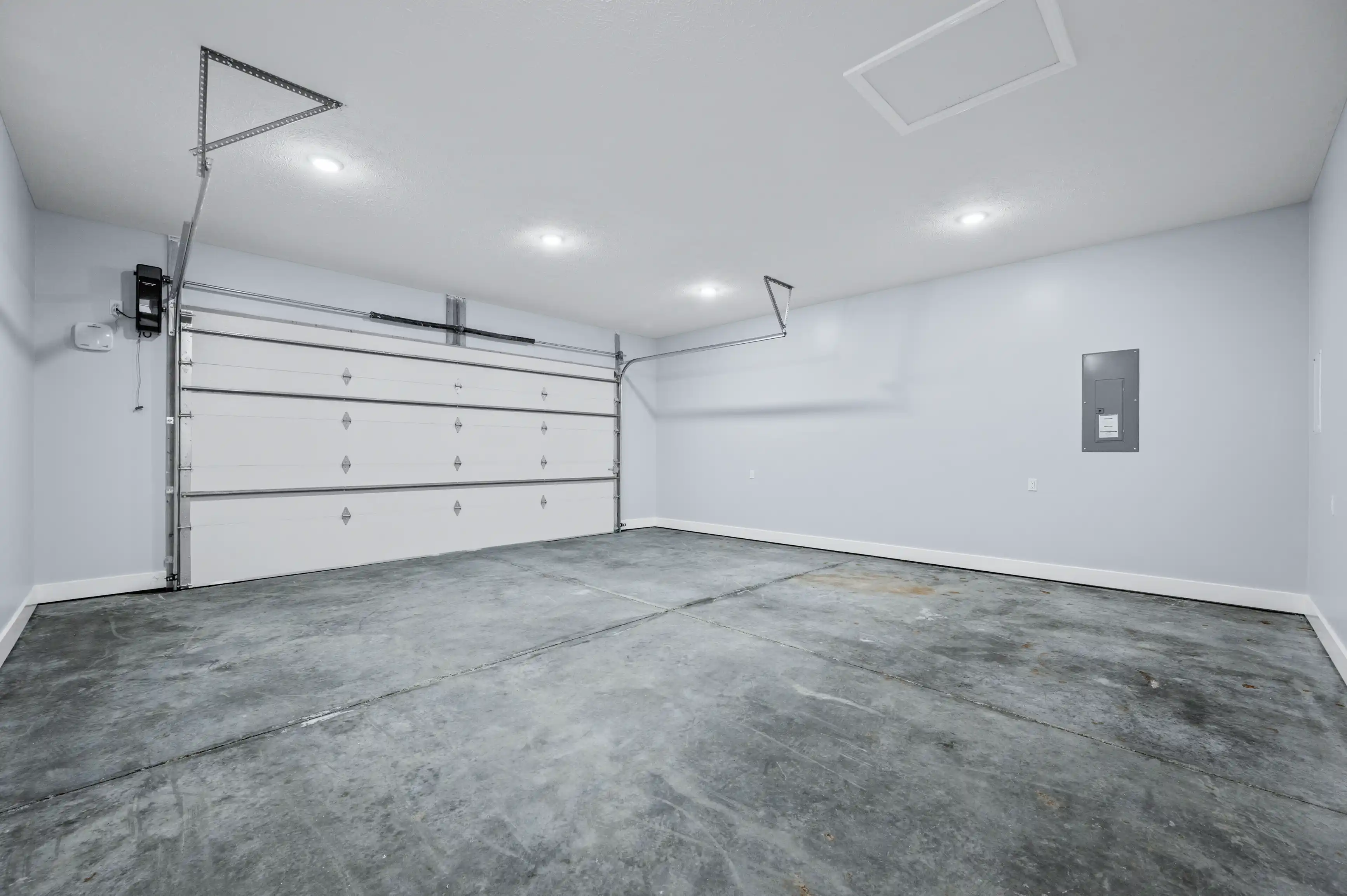 Empty two-car garage interior with a clean white wall and an automatic garage door.
