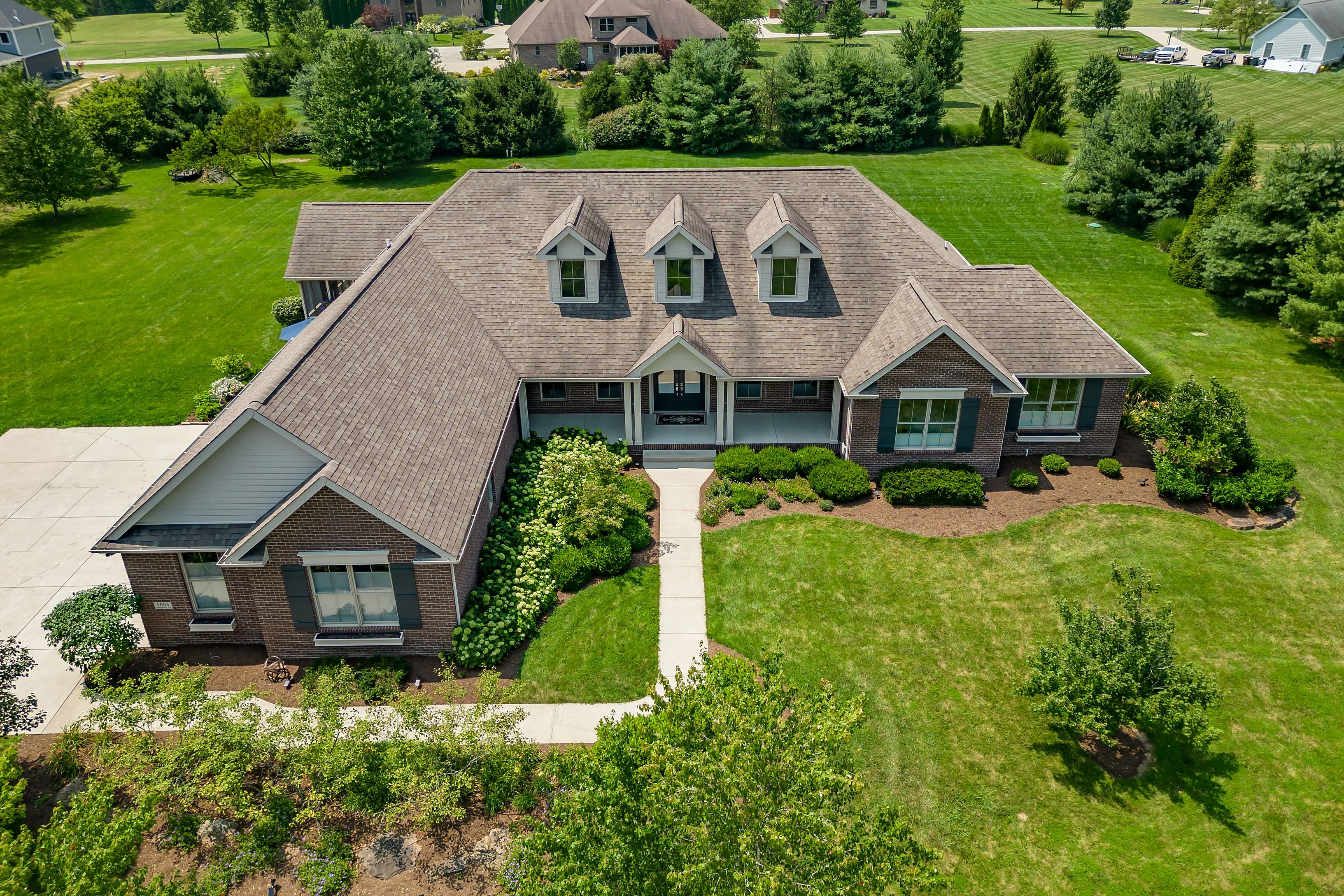 Aerial view of a large suburban home with a well-manicured lawn and landscaping.
