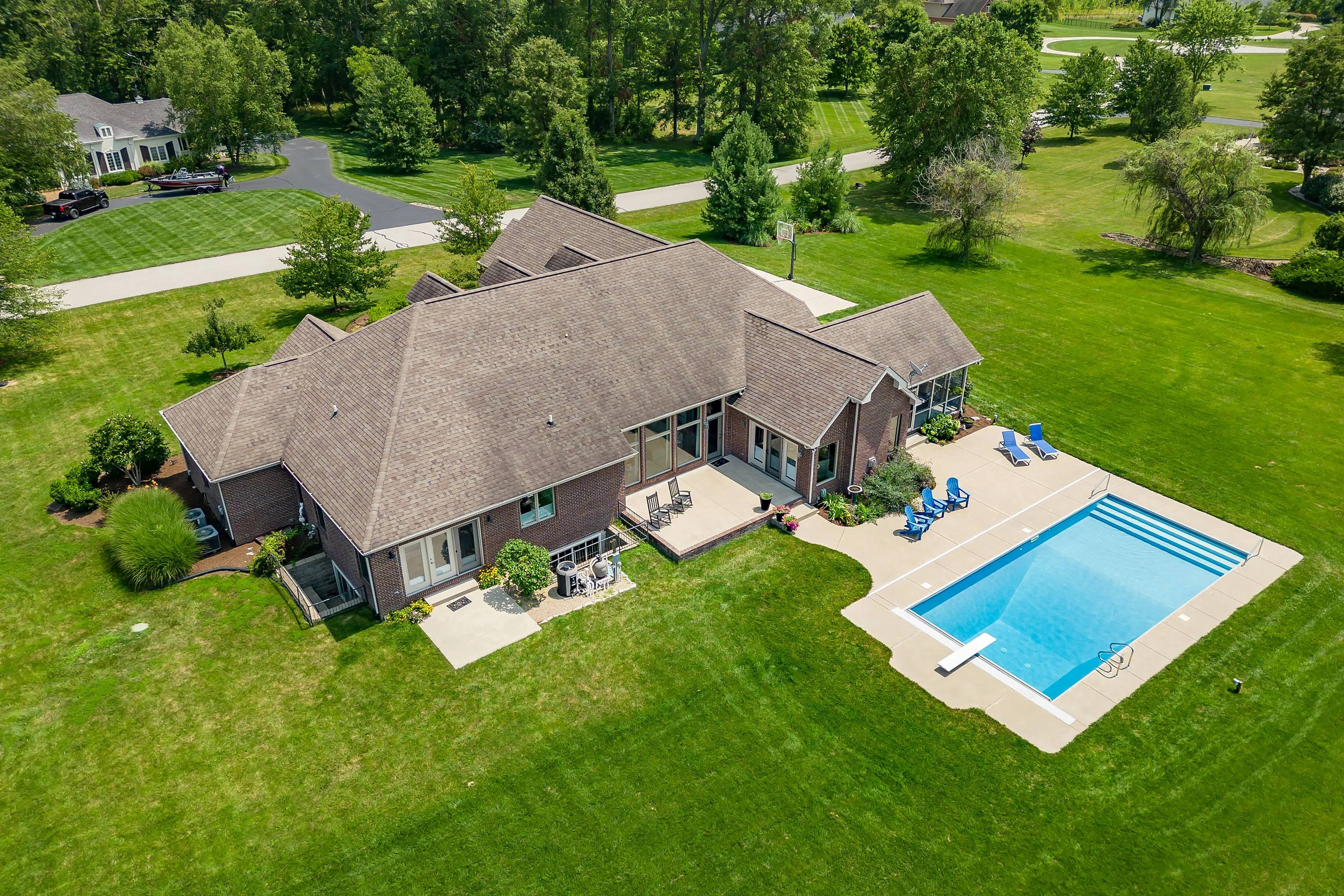 Aerial view of a suburban house with a large backyard and an outdoor swimming pool.