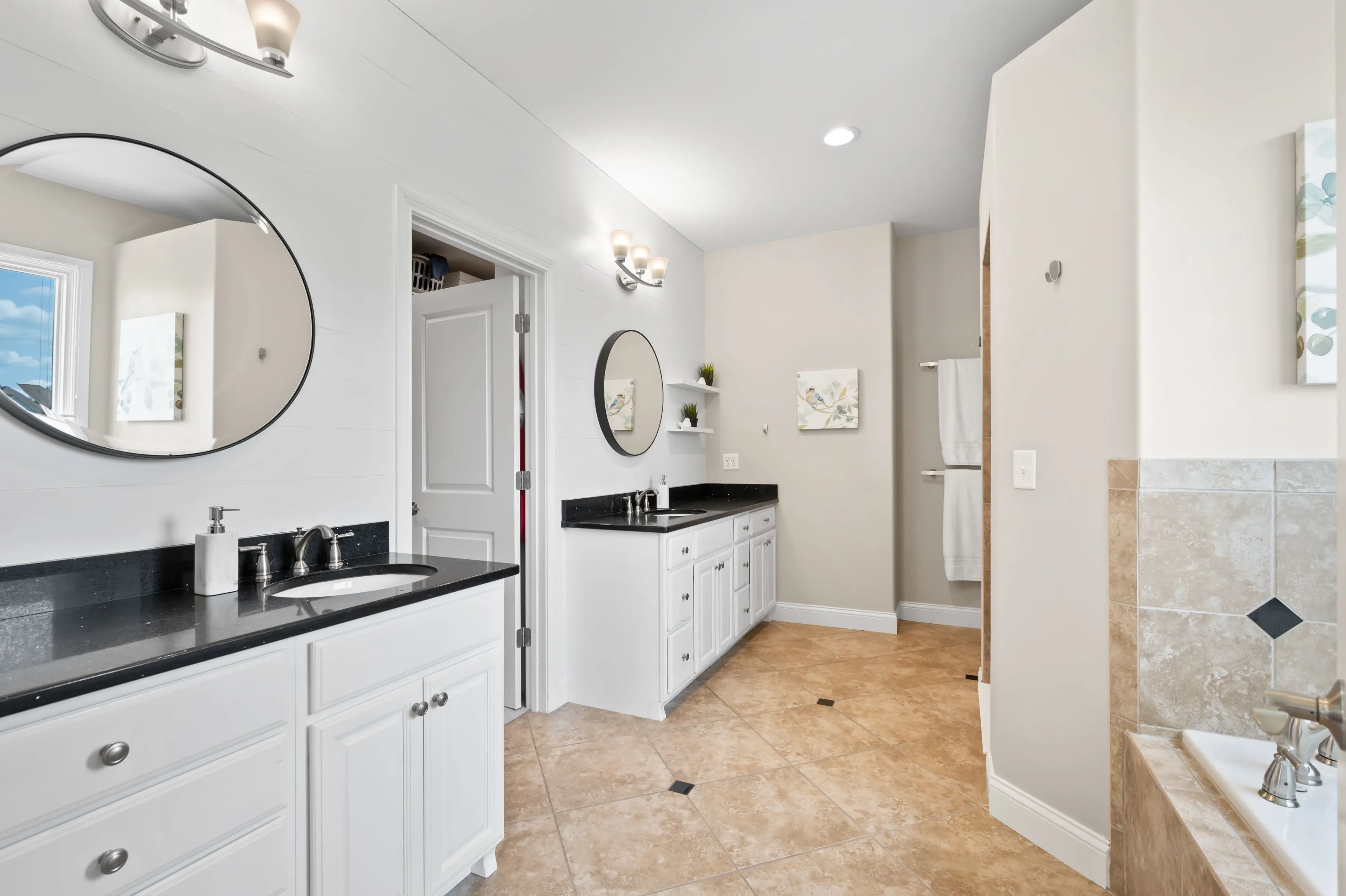 A modern bathroom with dual vanity sinks, large mirrors, and a separate shower and bathtub area.