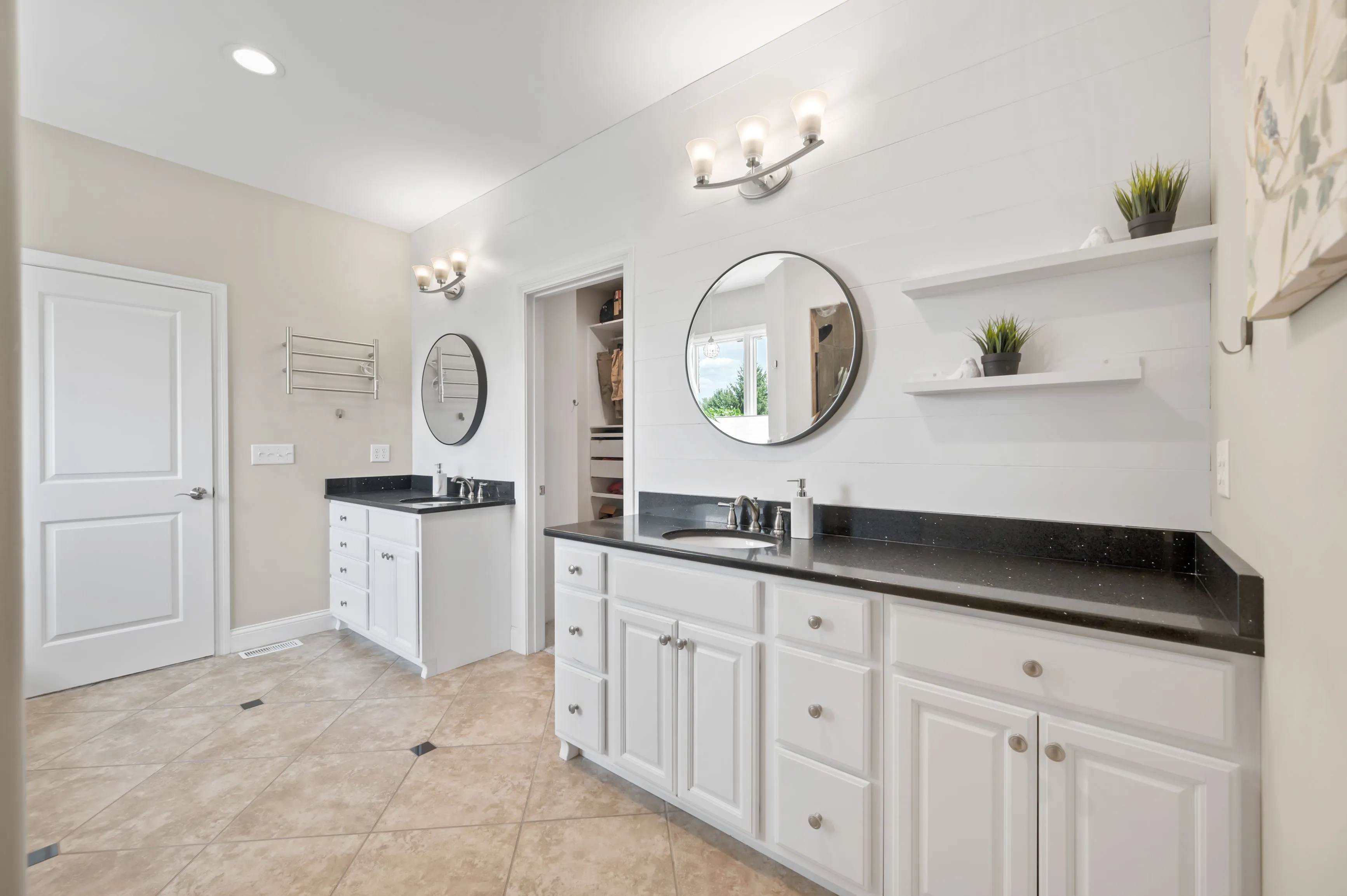Modern bathroom interior with dual vanity sinks, large mirrors, and white cabinets.