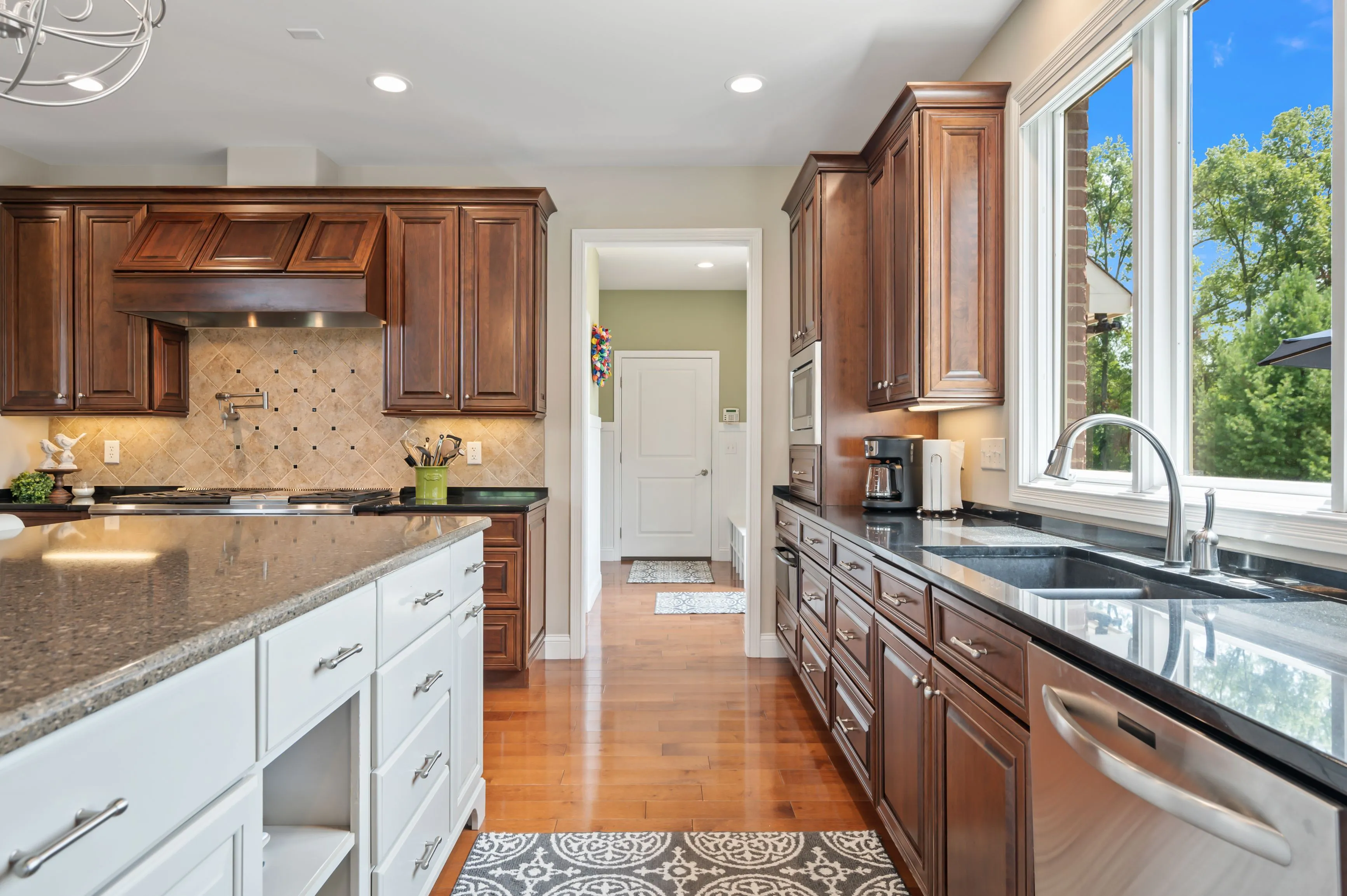 Modern kitchen interior with white and brown cabinets, granite countertops, and hardwood floors.