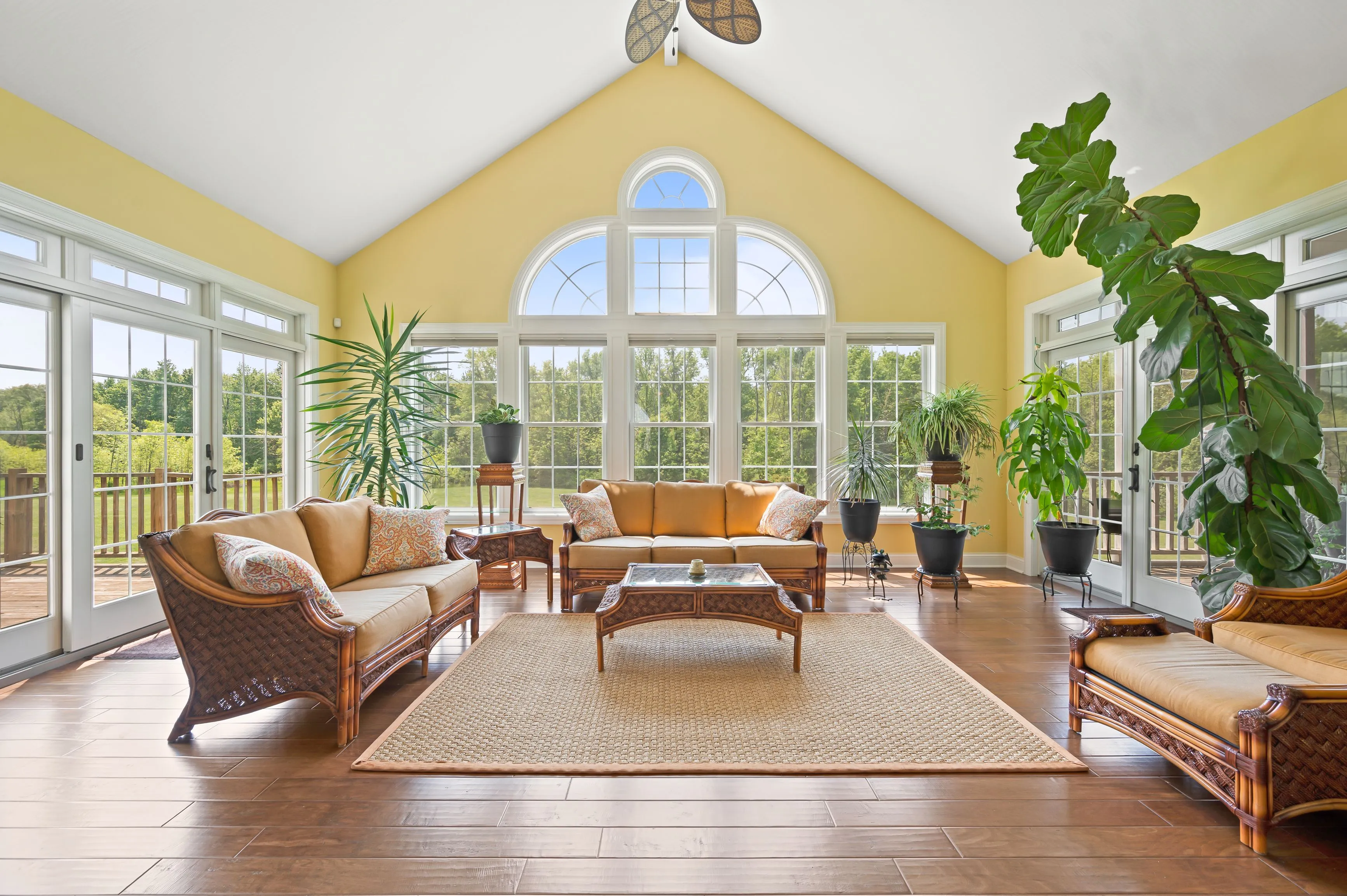 Bright and airy sunroom with large windows, wicker furniture, and indoor plants.