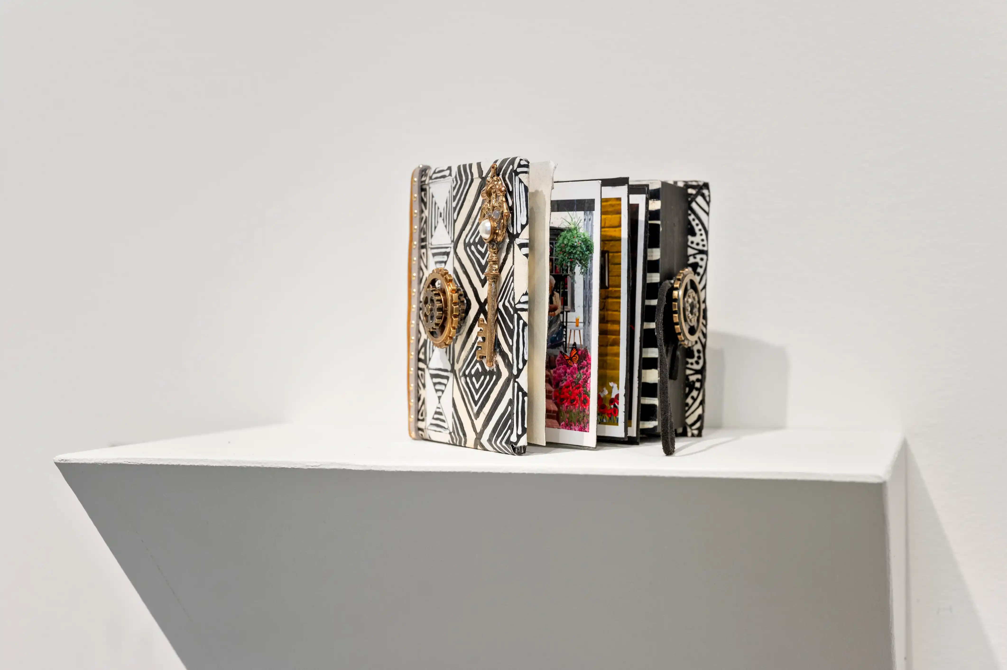 A collection of books with ornate covers displayed on a white shelf against a plain background.