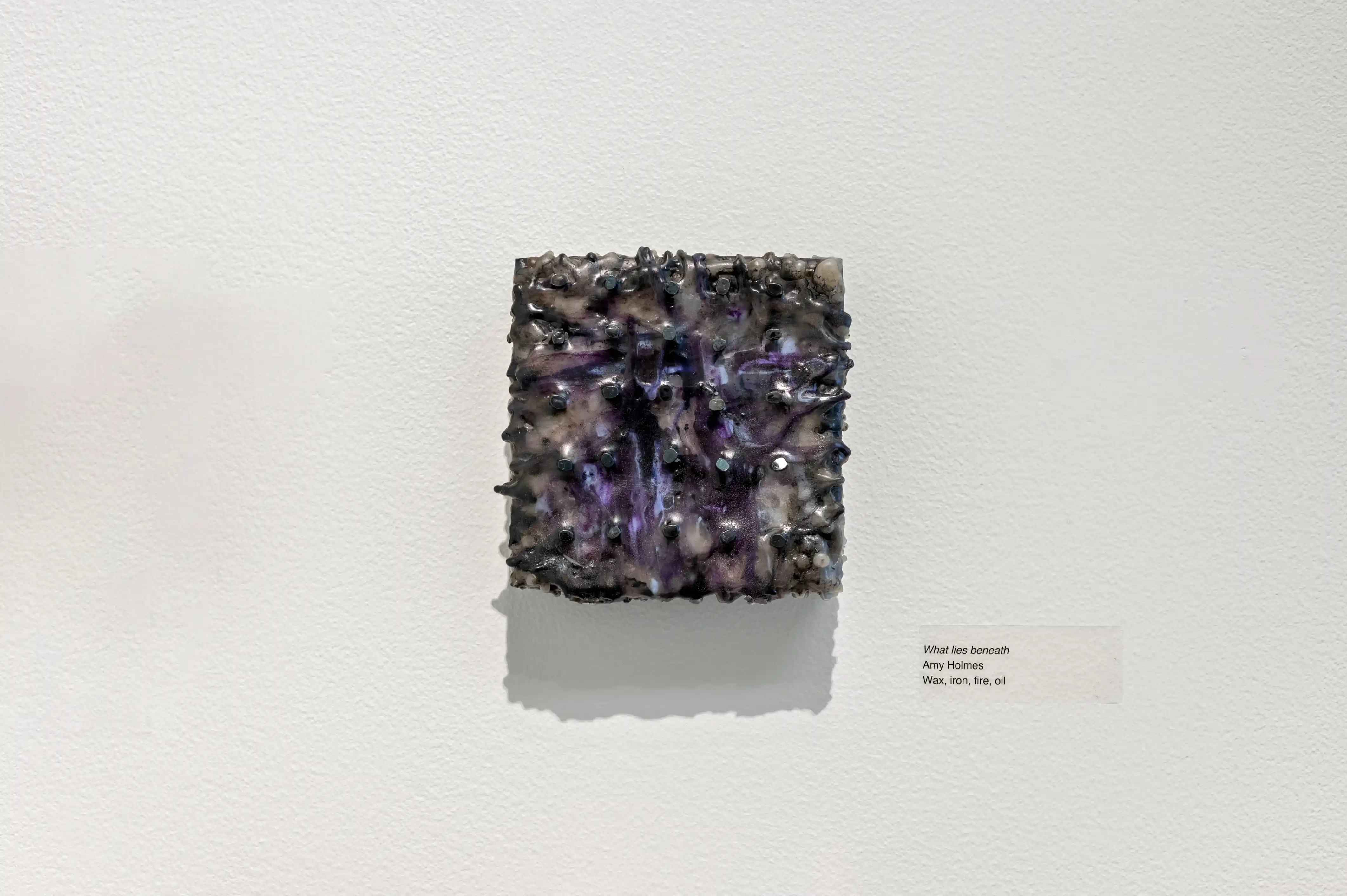 A cubic amethyst geode on display against a white background with a small descriptive label to the side.