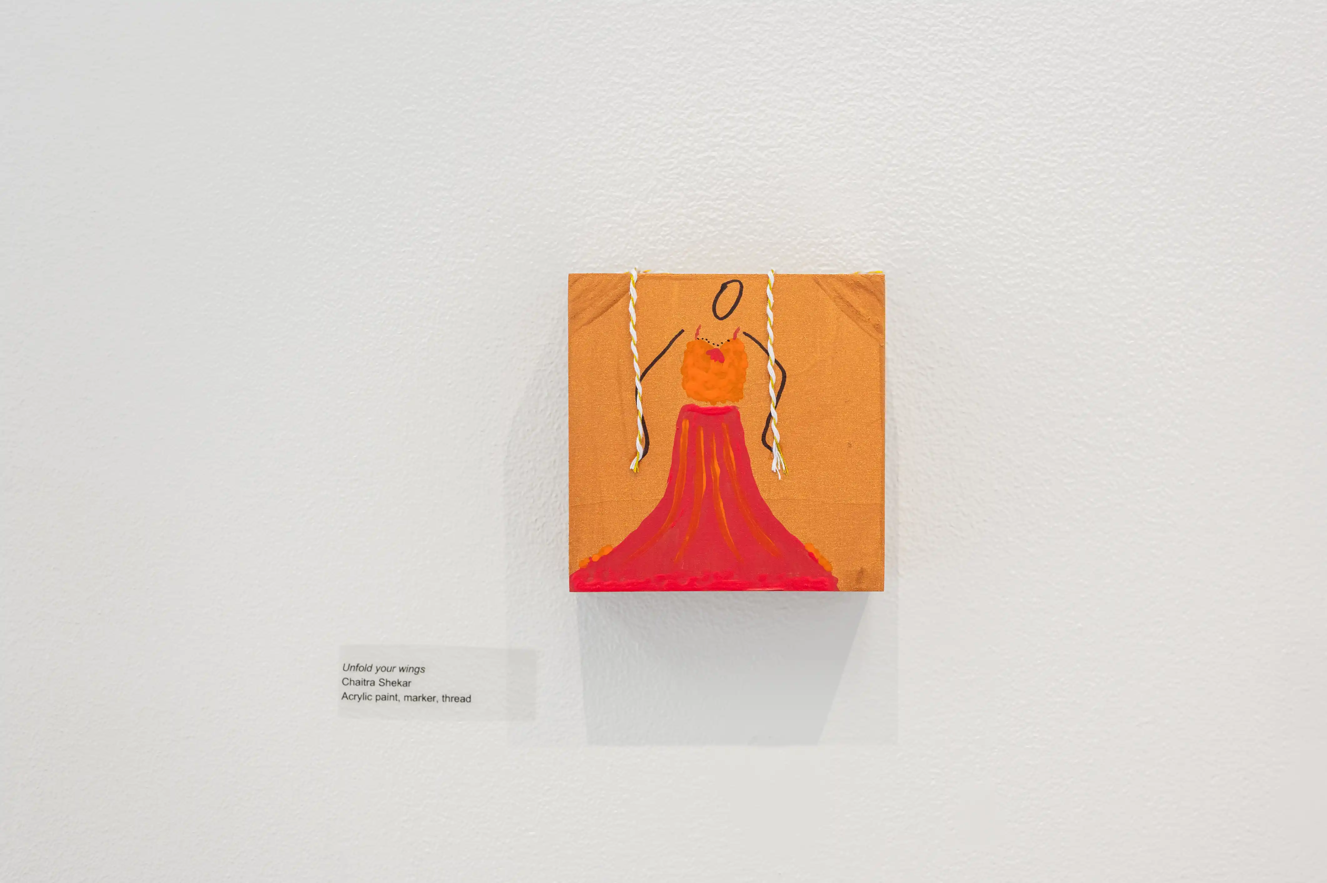 Modern art painting depicting a red dress on an orange background displayed in a gallery, with an information plaque on the wall to the left.