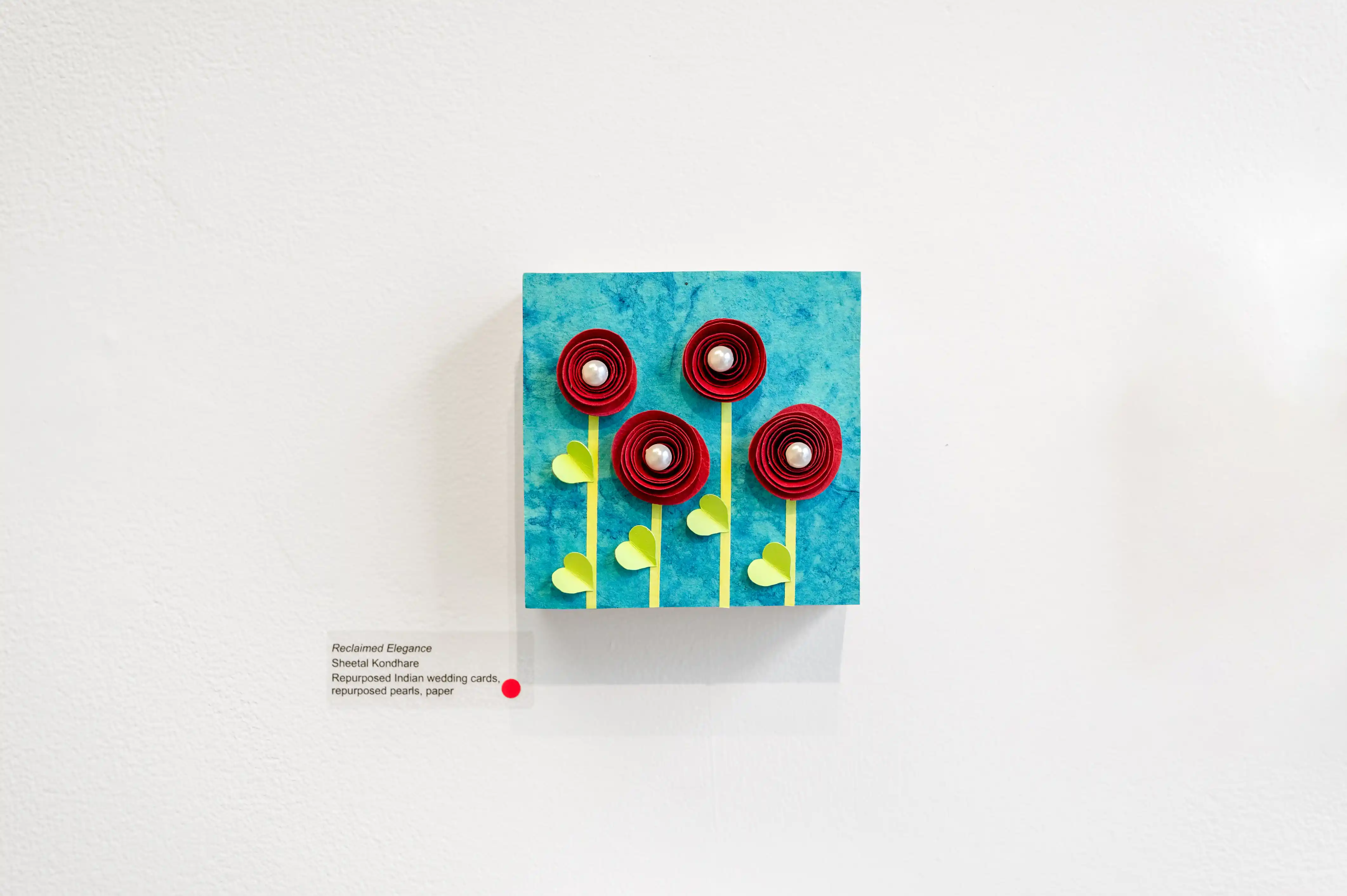 Abstract artwork displayed on a gallery wall featuring blue texture with red and yellow circular elements.