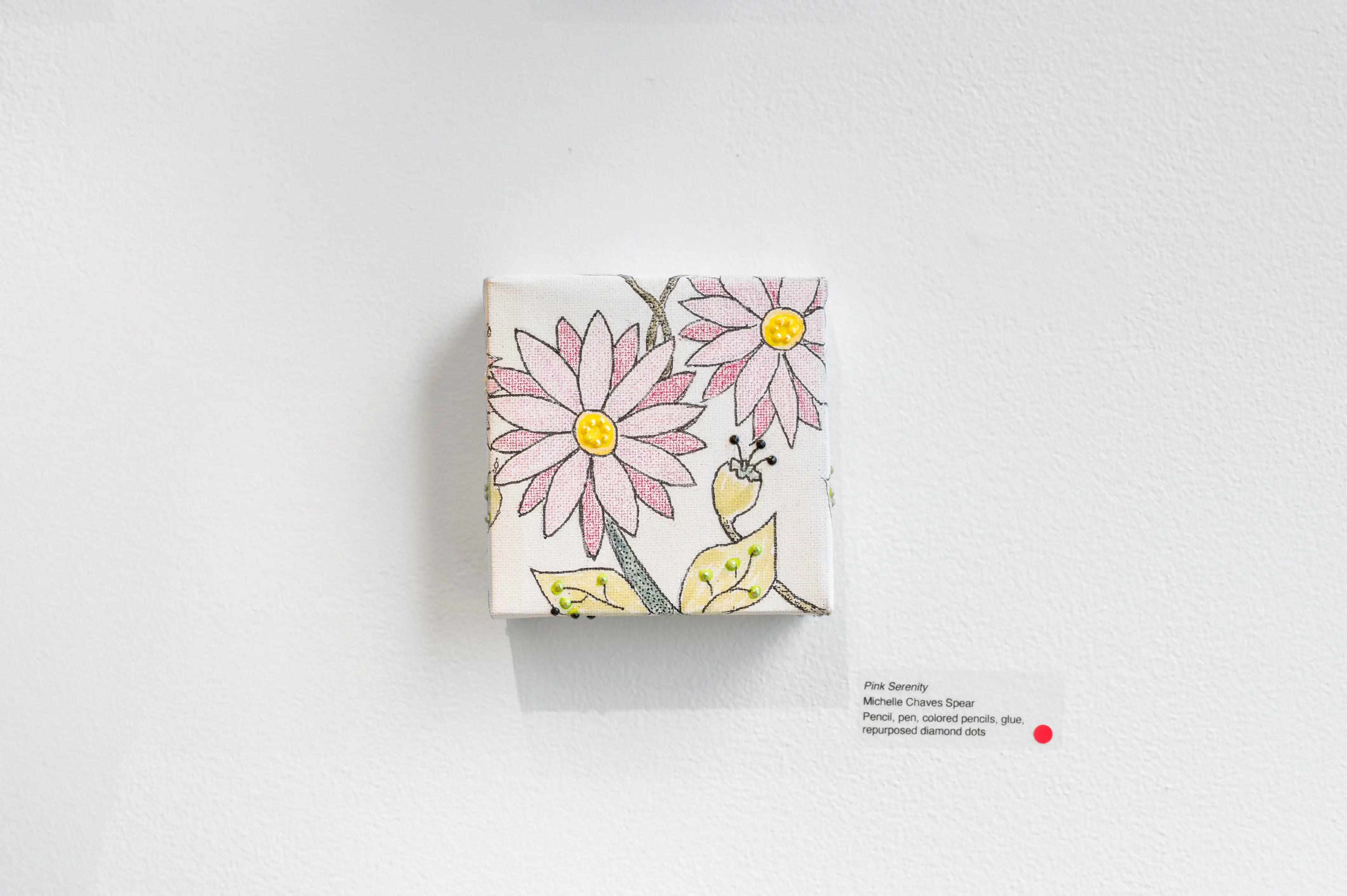 Canvas with pink and yellow flowers hanging on a white wall, accompanied by a description card and a red heart-shaped sticker indicating a sale or appreciation.