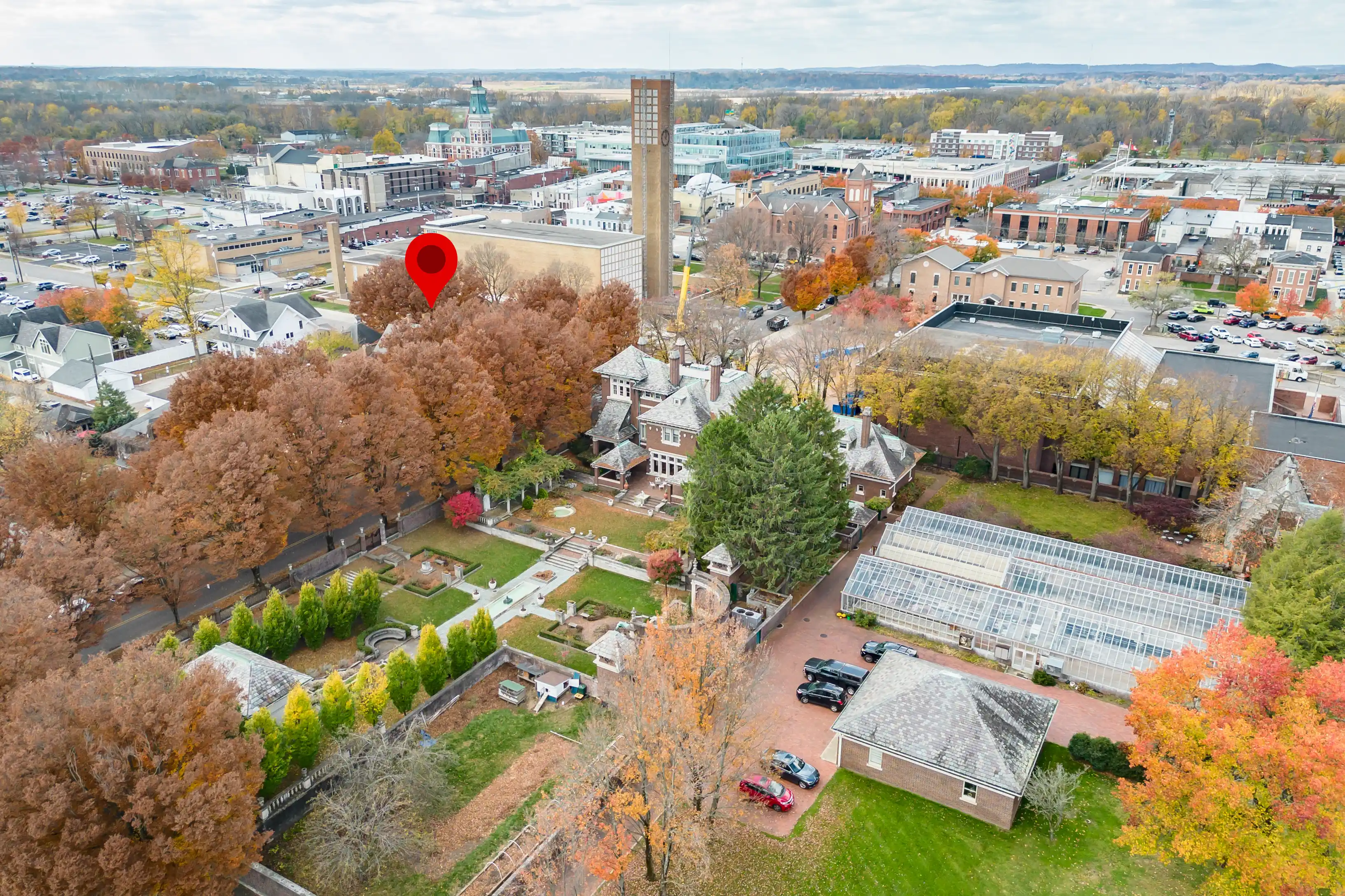 Aerial view of a town with a mixture of residential and commercial buildings, autumn-colored trees, and a prominent clock tower near the center.