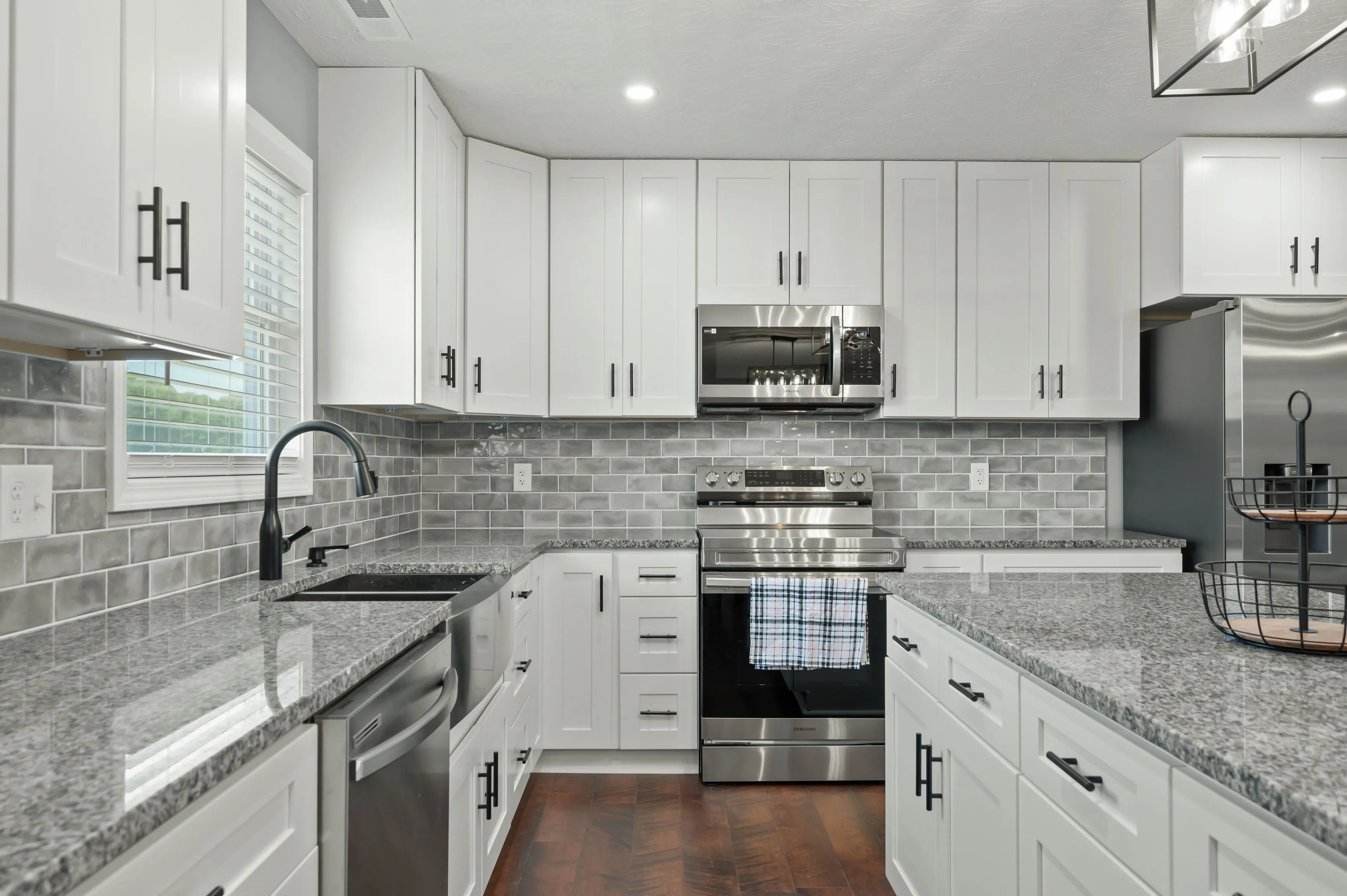 Modern kitchen interior with white cabinets, stainless steel appliances, and gray subway tile backsplash.