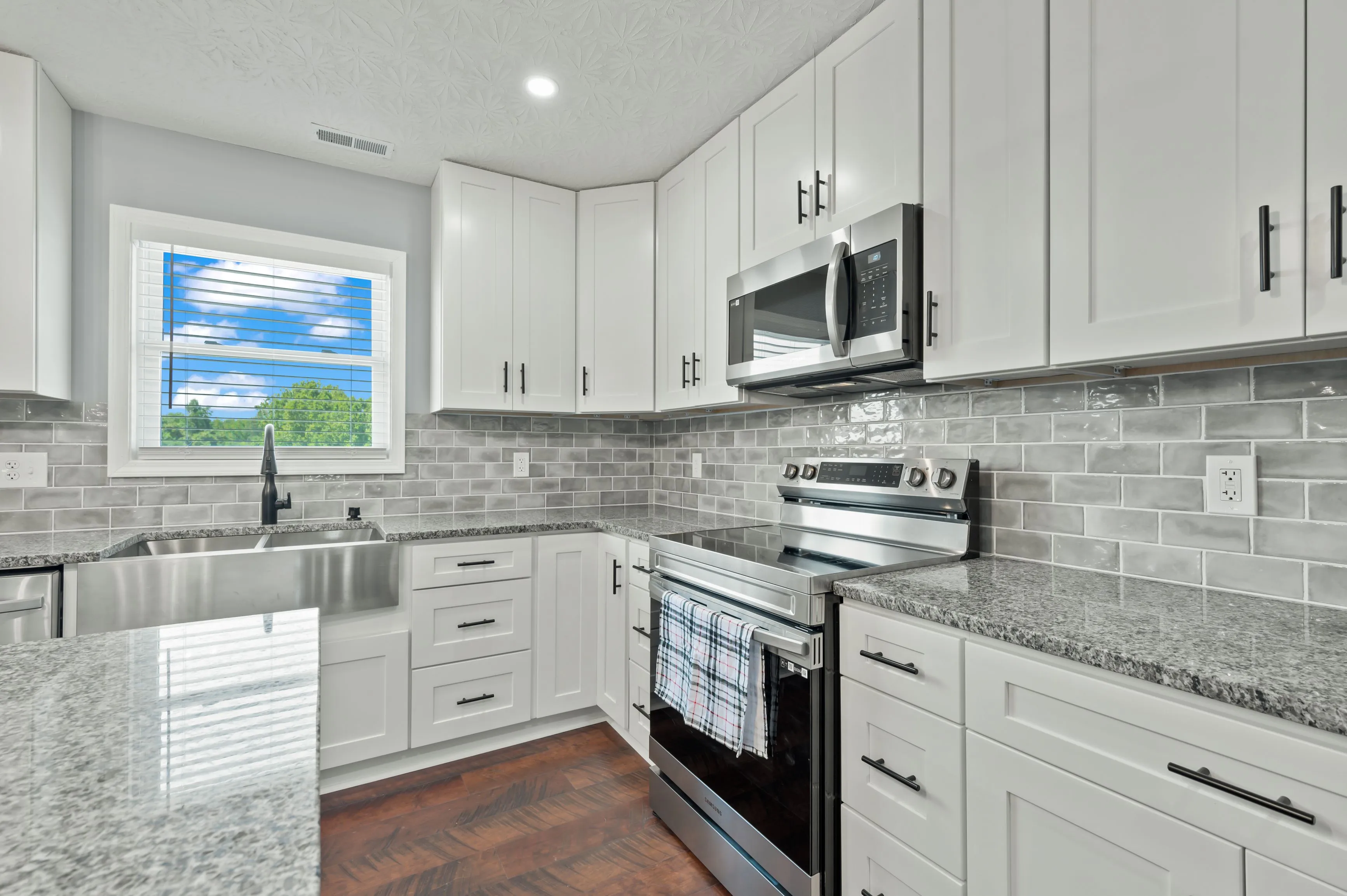 Modern kitchen interior with white cabinetry, stainless steel appliances, and grey subway tile backsplash.