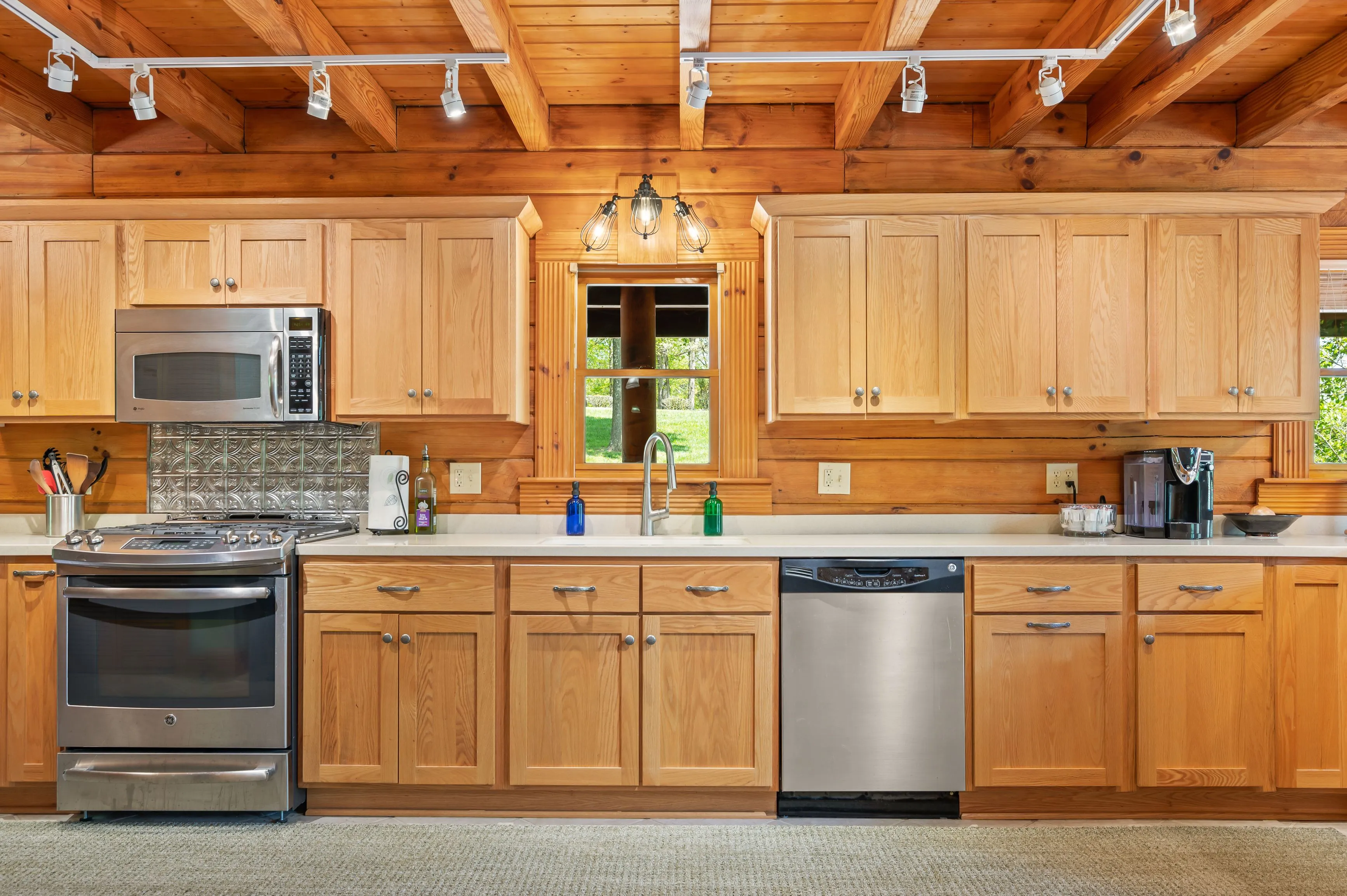 Rustic kitchen interior with wooden cabinets and appliances, including a stainless steel dishwasher and black stove.