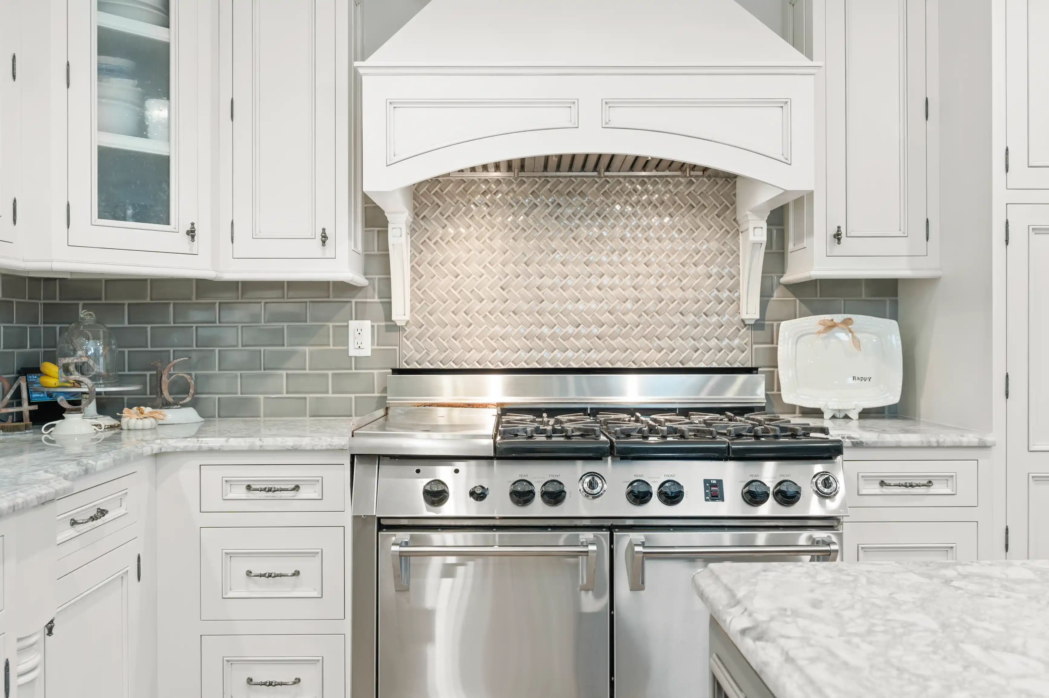 Modern kitchen with stainless steel gas stove, white cabinetry, and gray subway tile backsplash.