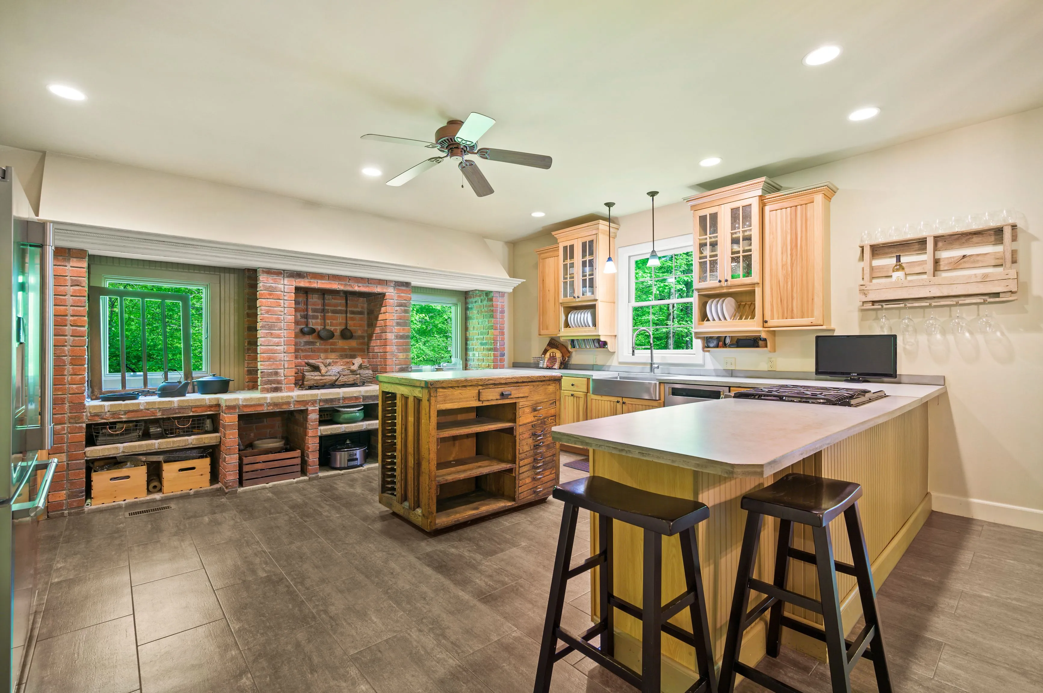 Modern kitchen interior with a brick wall, stainless steel appliances, and a central island with stools.