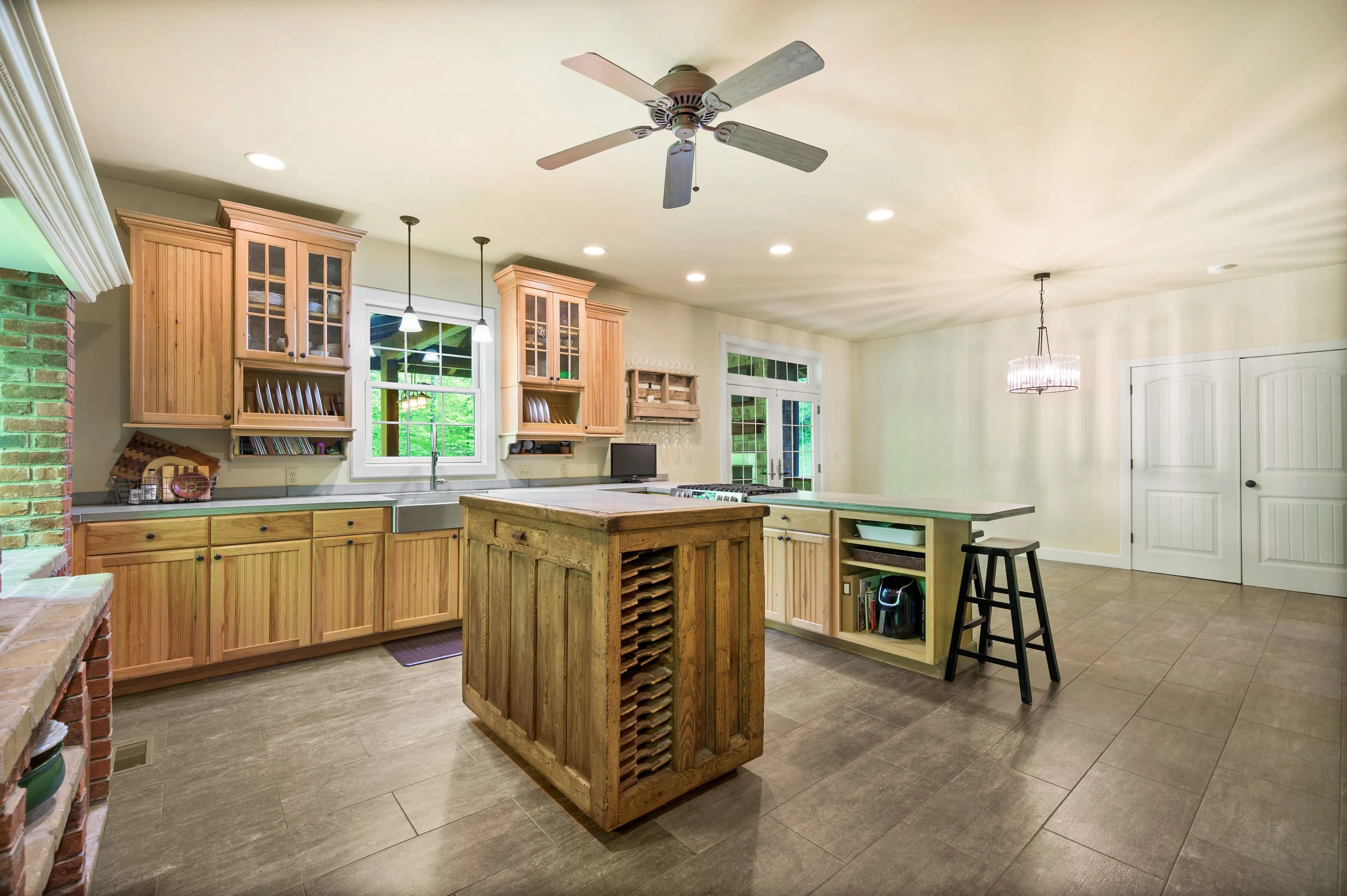 Spacious kitchen interior with wooden cabinets, central island, modern appliances, and pendant lighting.