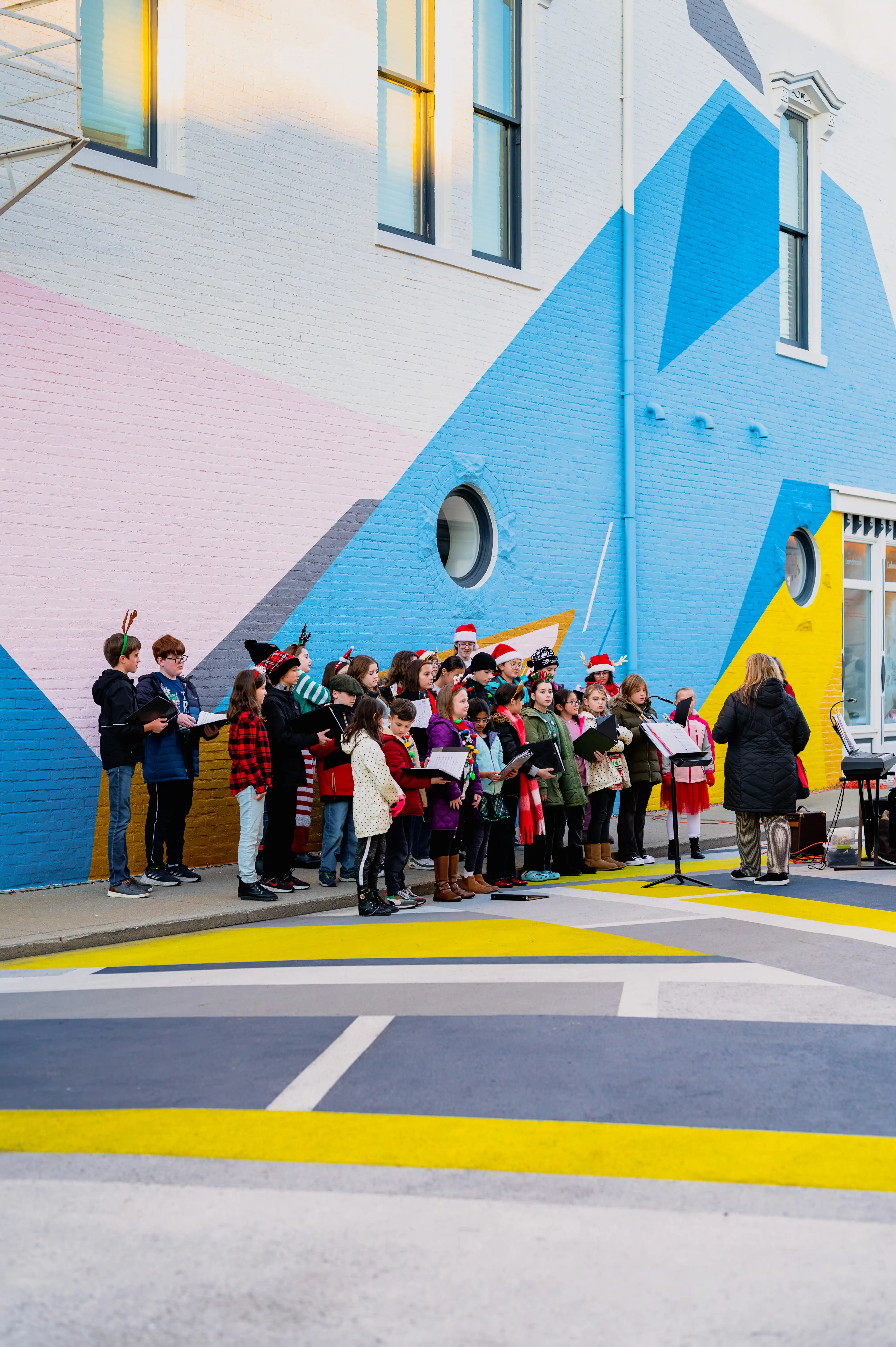 A group of people gathered outside a colorful building with blue and yellow geometric shapes on the facade.