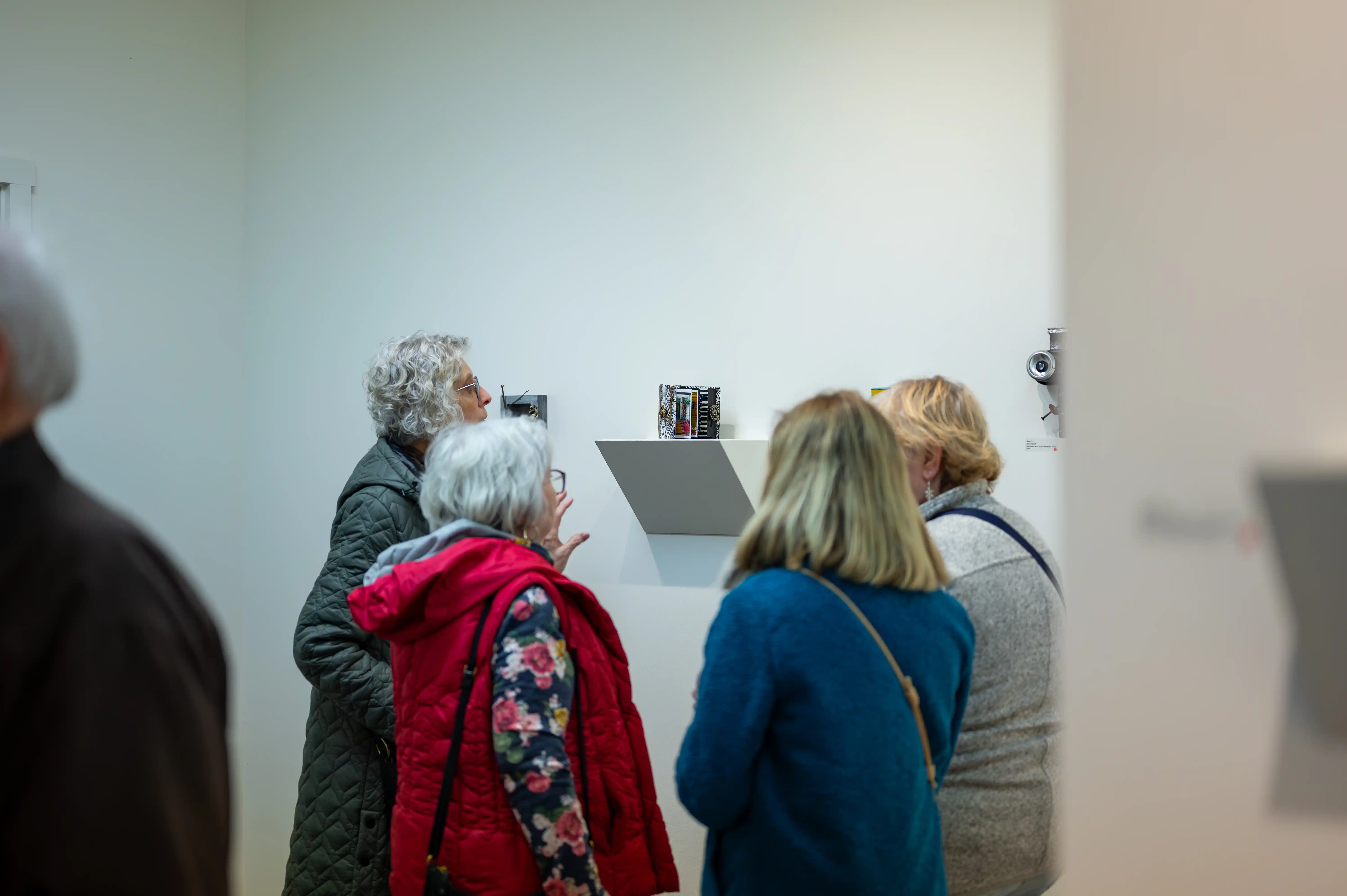 Group of people viewing art in a gallery setting.