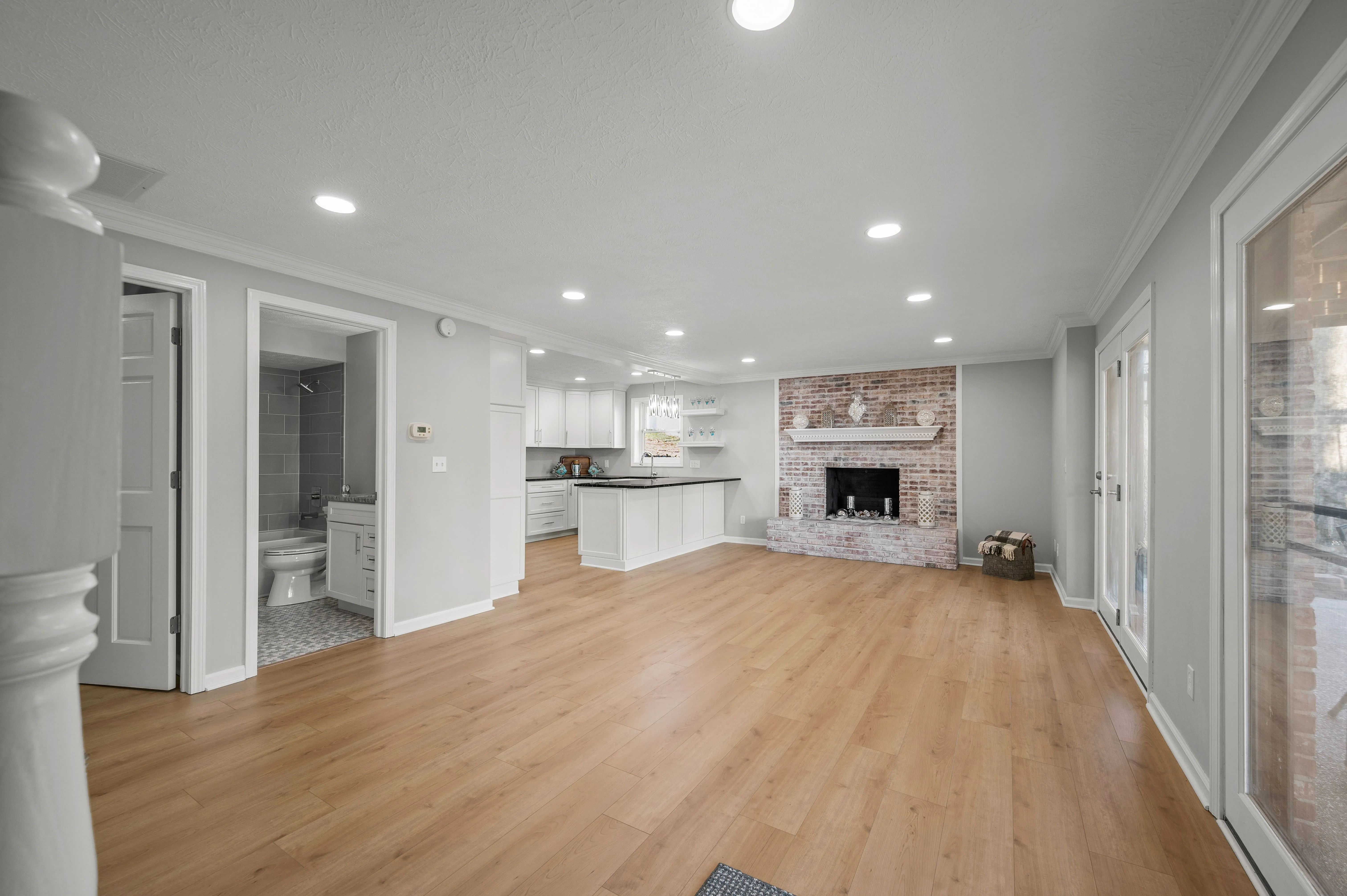 Spacious, well-lit living space with hardwood floors, a fireplace, and an open floor plan leading to the kitchen.
