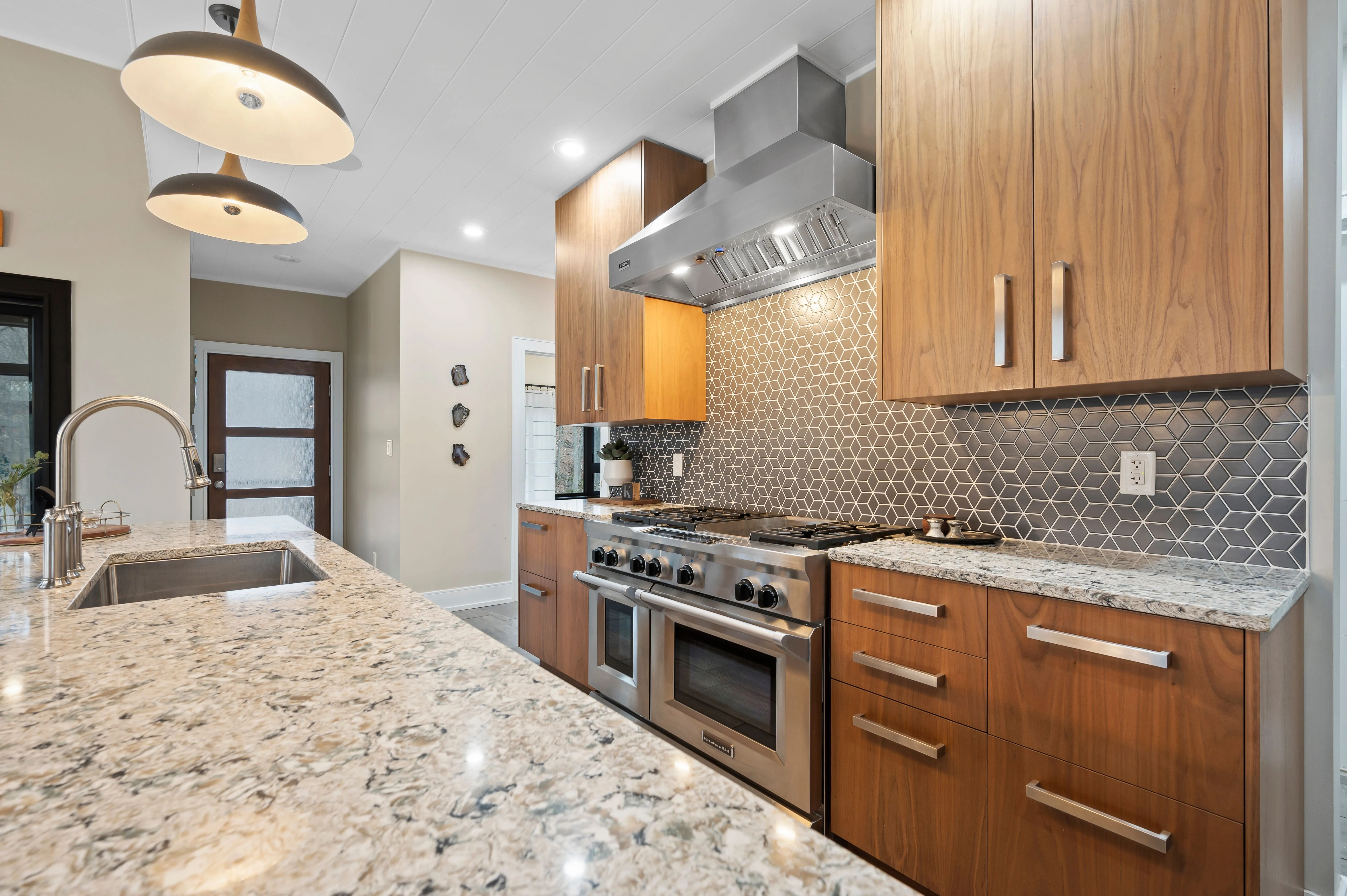 Modern kitchen interior with wood cabinets, granite countertops, and stainless steel appliances.