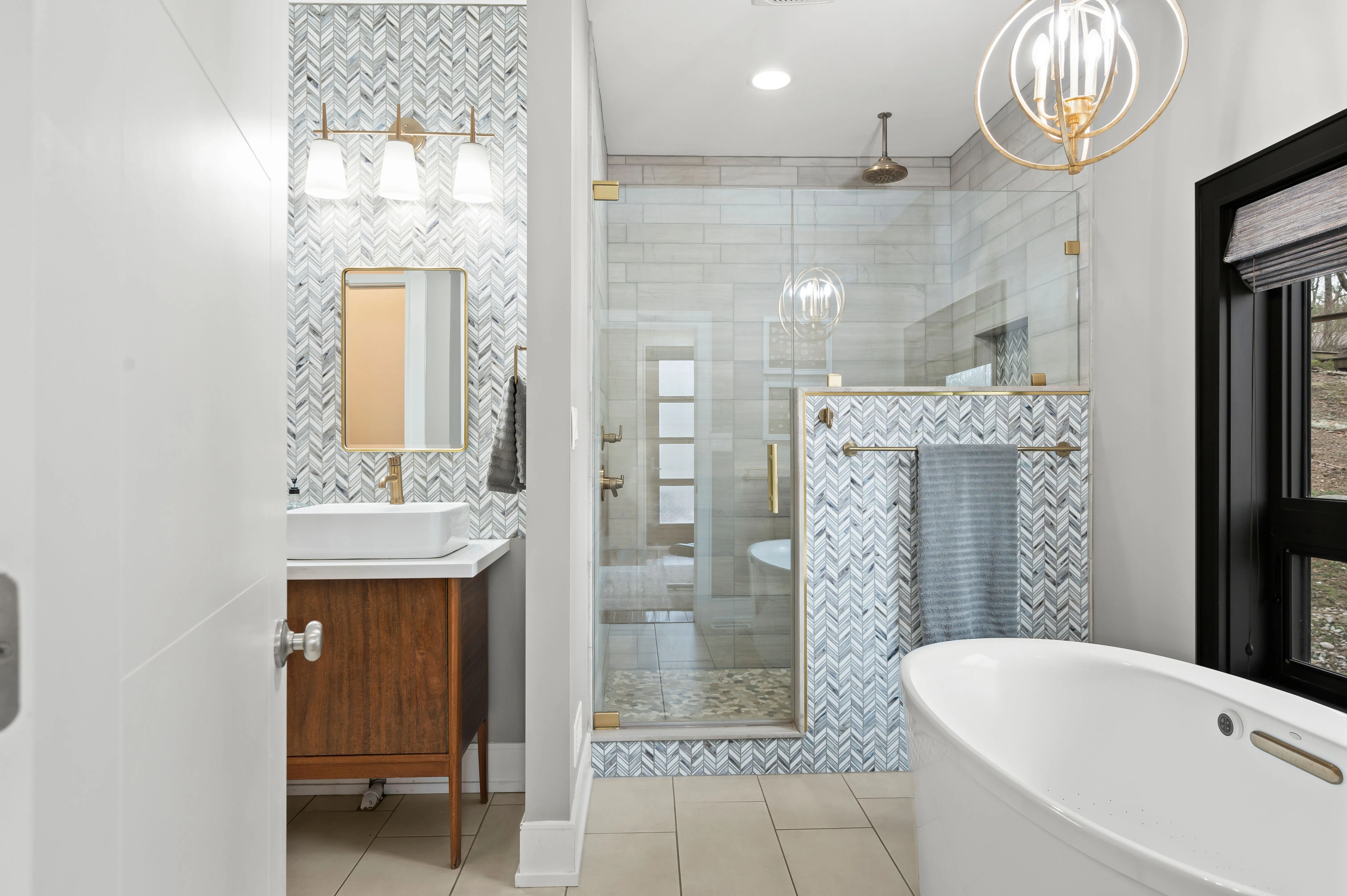 Modern bathroom interior with a freestanding tub, glass shower, patterned tiles, and elegant lighting.