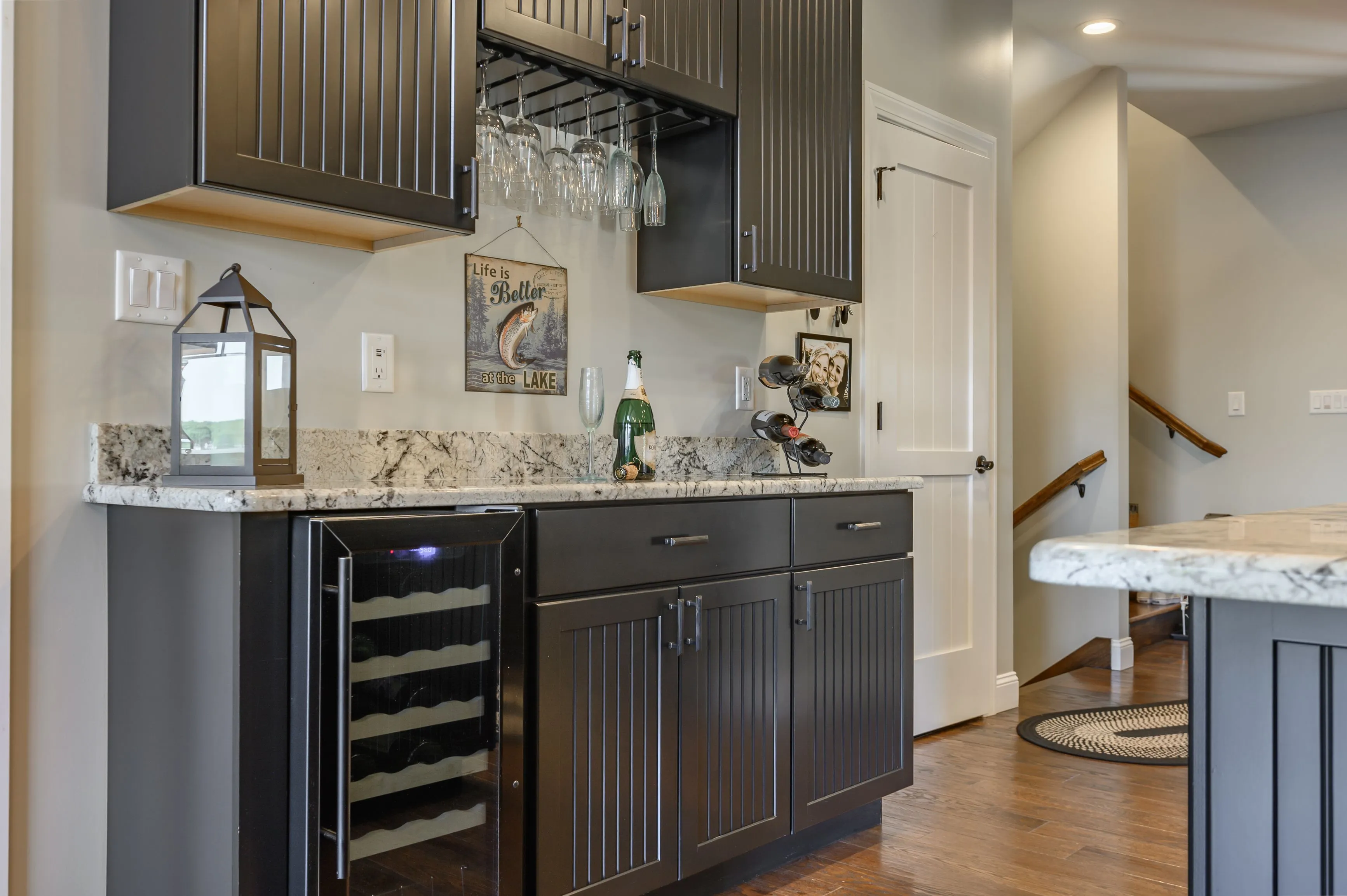 Modern kitchen interior with dark wood cabinets, granite countertops, and a built-in wine cooler.