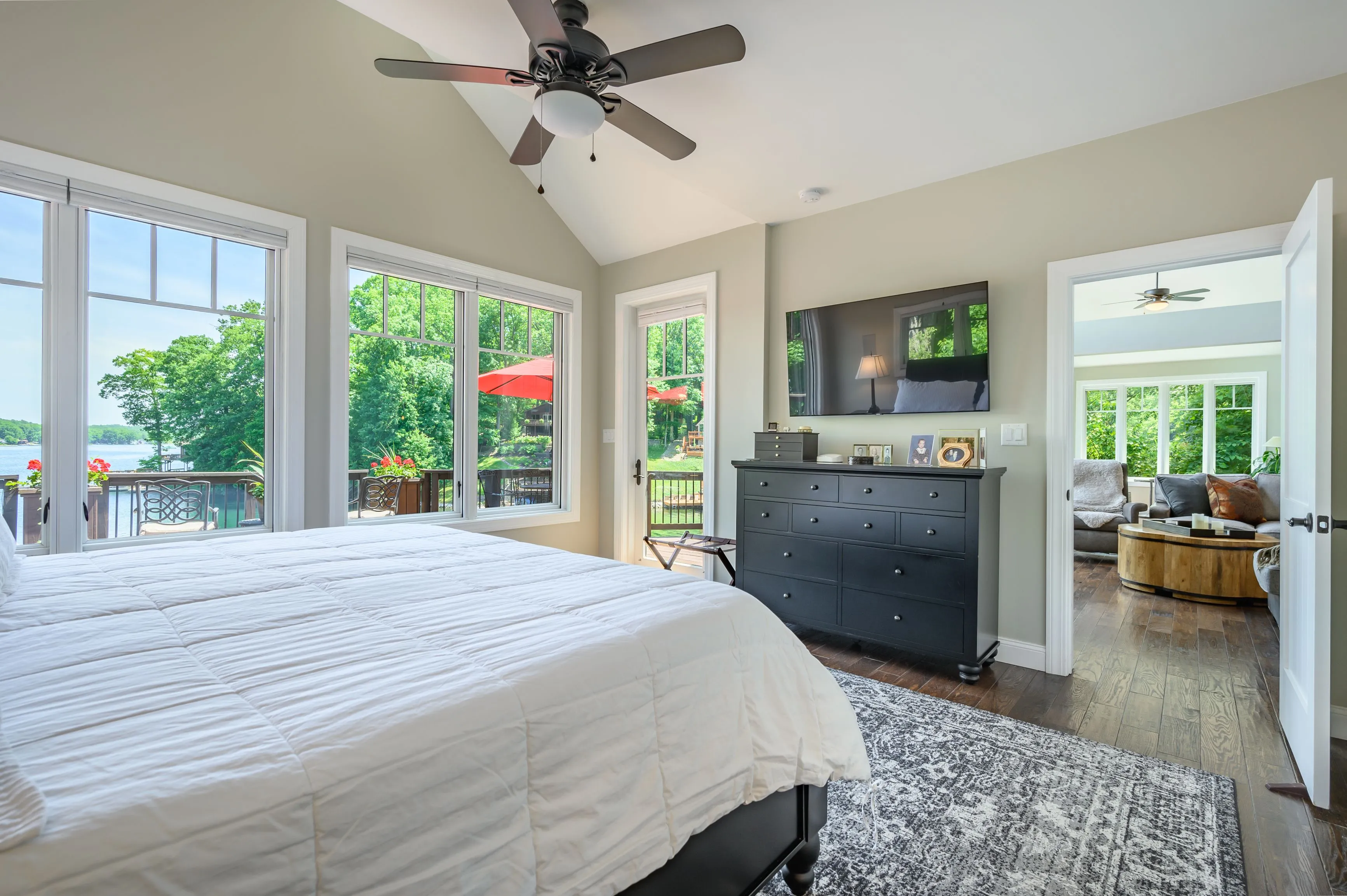 Bright and airy bedroom with a large bed, ceiling fan, and open French doors leading to a balcony.