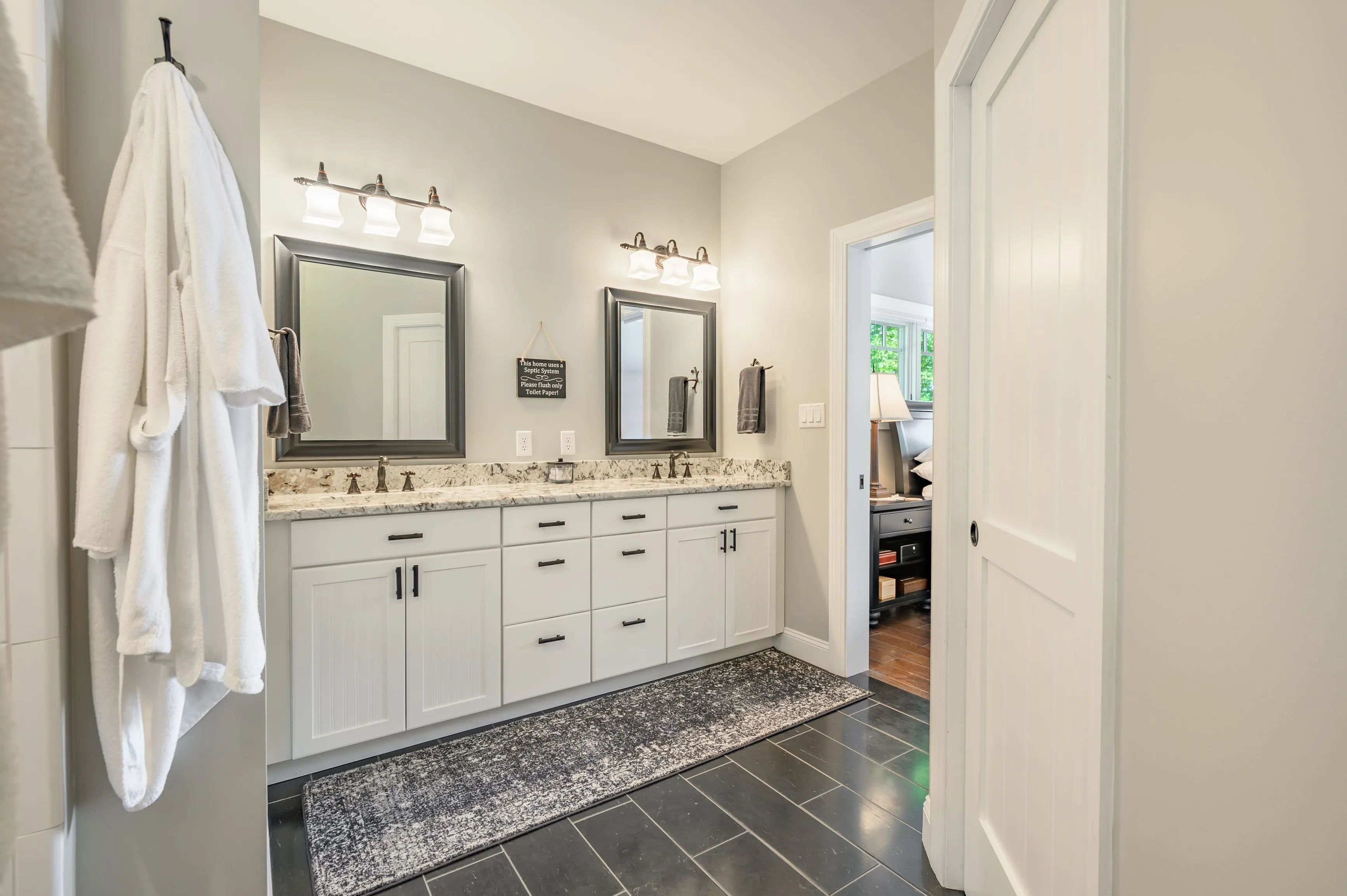 A clean and well-lit modern bathroom with double vanity sinks, large mirrors, and a patterned tile floor.