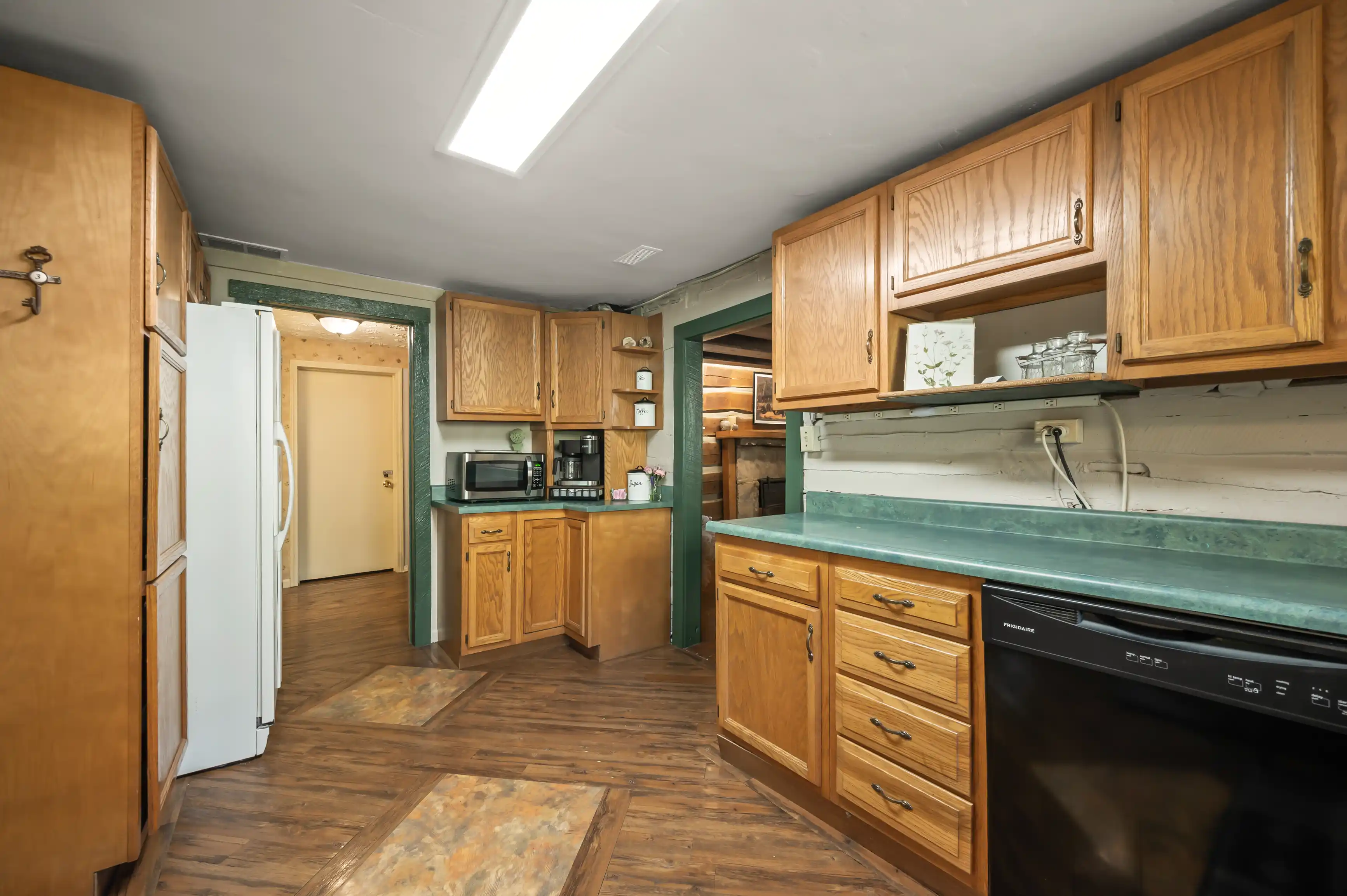 Interior of a dated kitchen with wooden cabinets, white appliances, and green countertops.