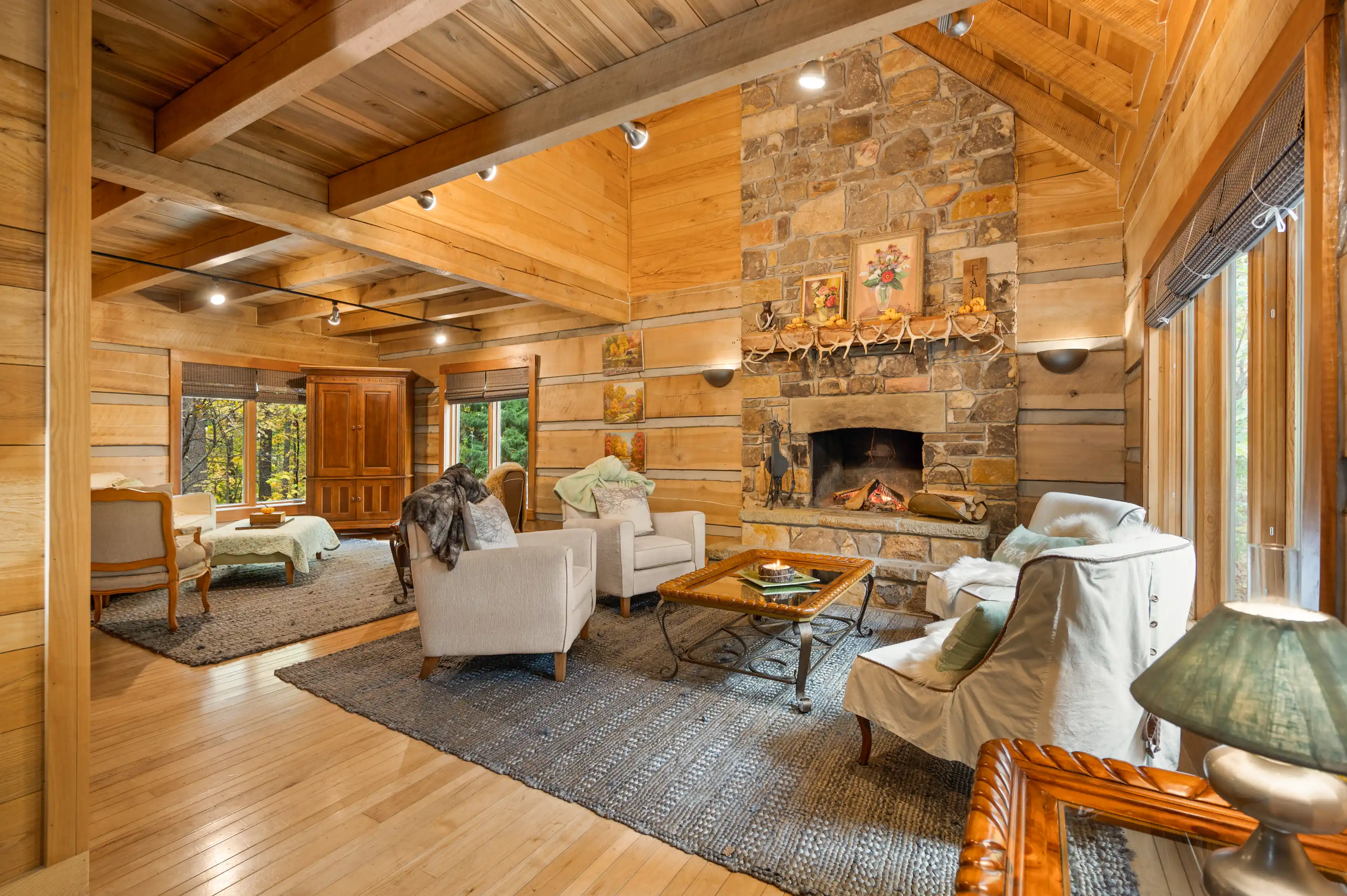 Cozy cabin living room interior with a stone fireplace, wooden walls, and rustic furniture.
