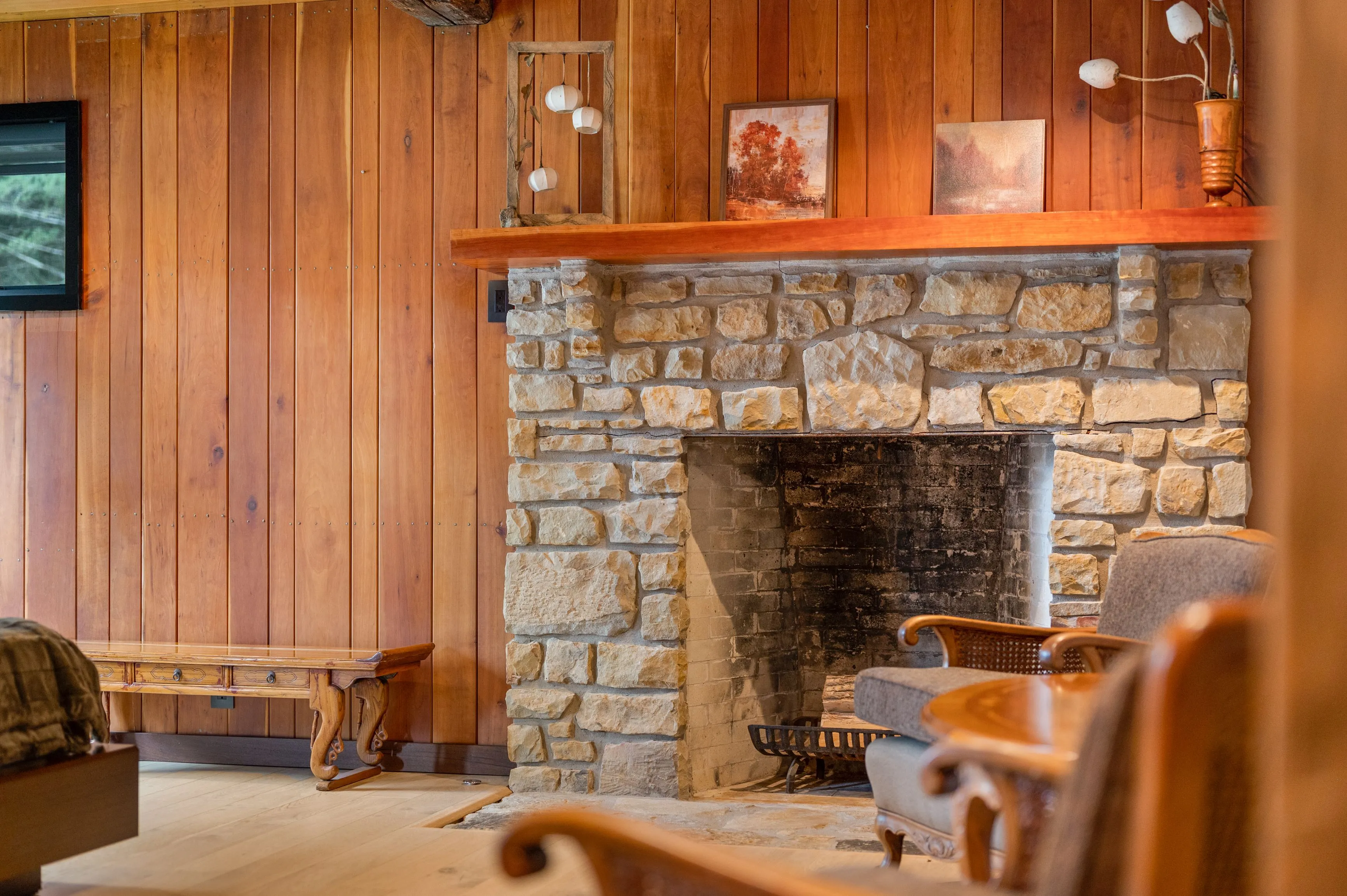 Cozy cabin interior with wooden walls, a stone fireplace, and traditional furniture.