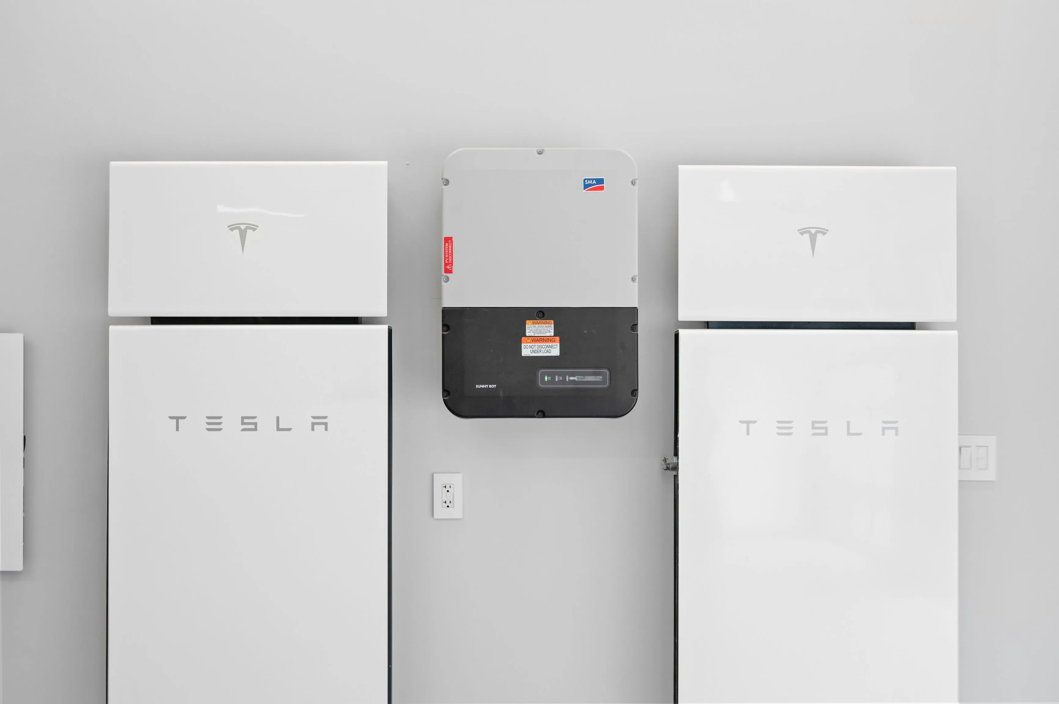 Wall-mounted Tesla Powerwalls and Solar Inverter in a clean, organized home energy setup.