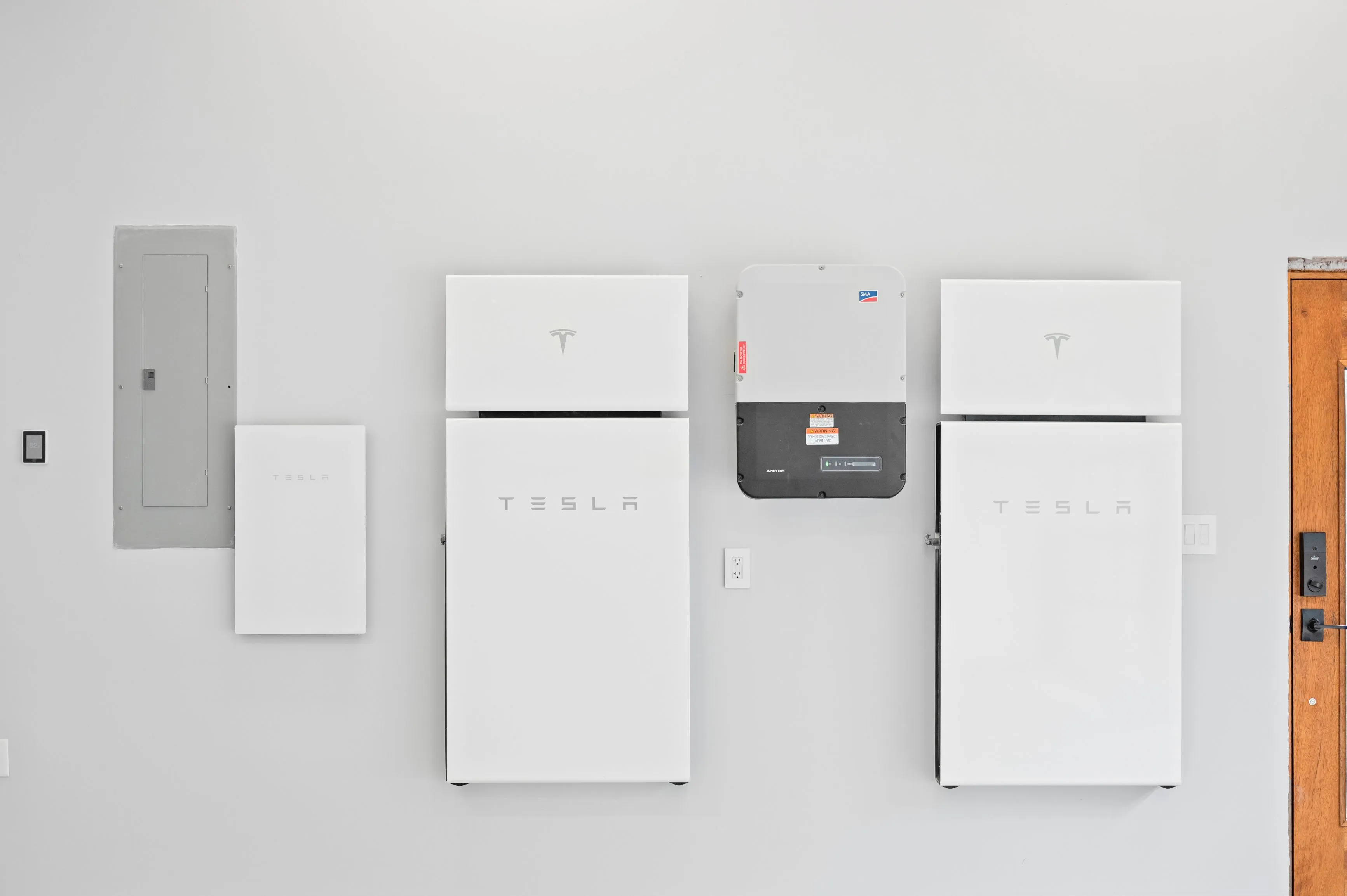 Wall-mounted Tesla Powerwall batteries and backup gateway in a residential garage.