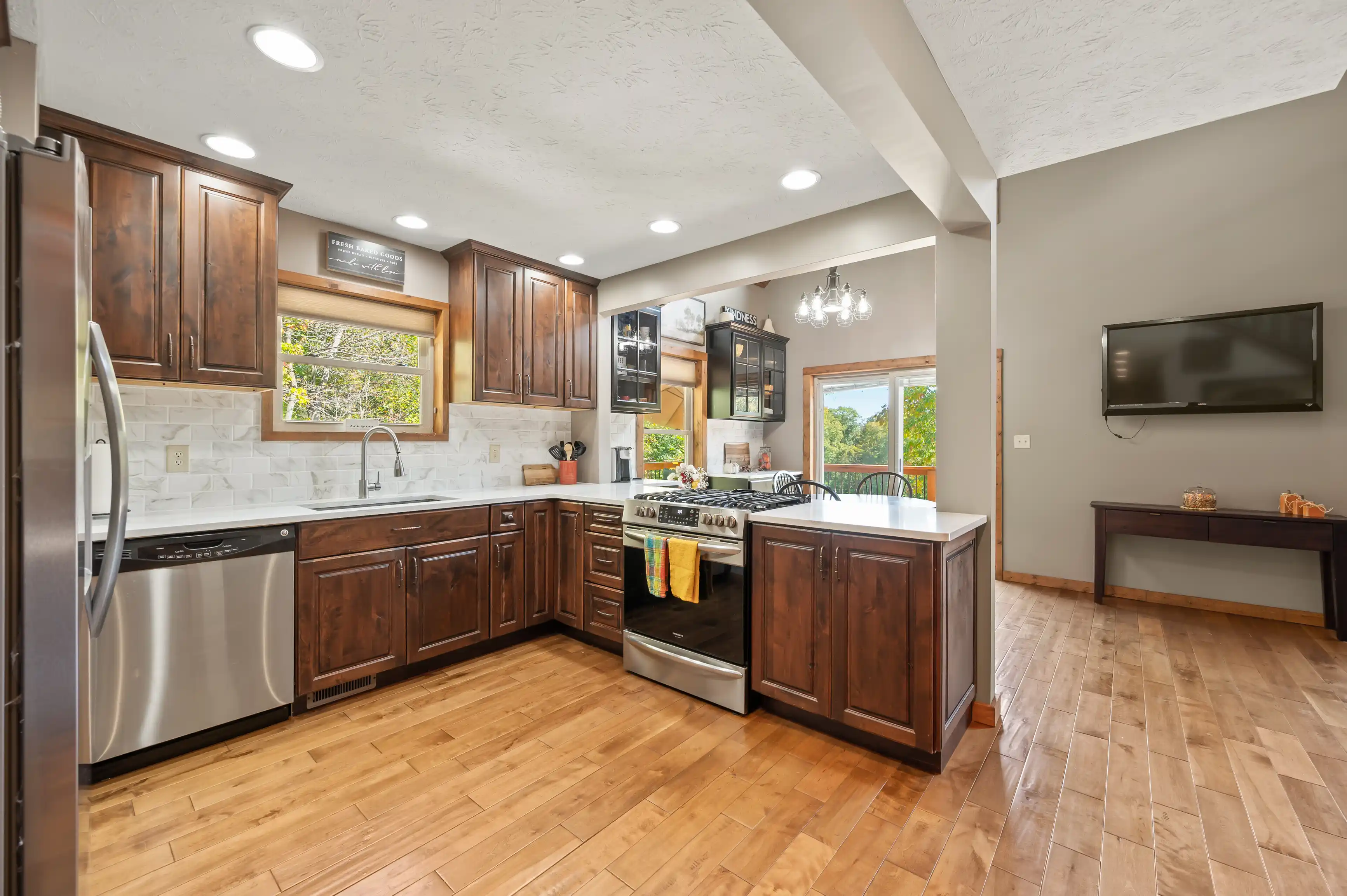 Modern kitchen interior with wooden cabinets, stainless steel appliances, and a hardwood floor.